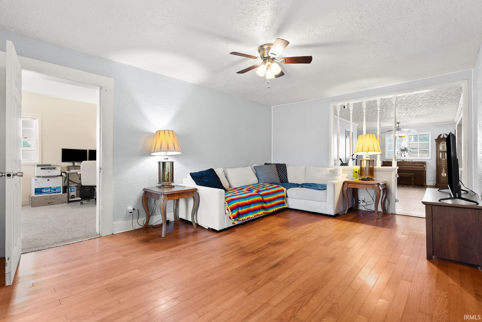 Living area with a textured ceiling, a ceiling fan, and hardwood / wood-style flooring
