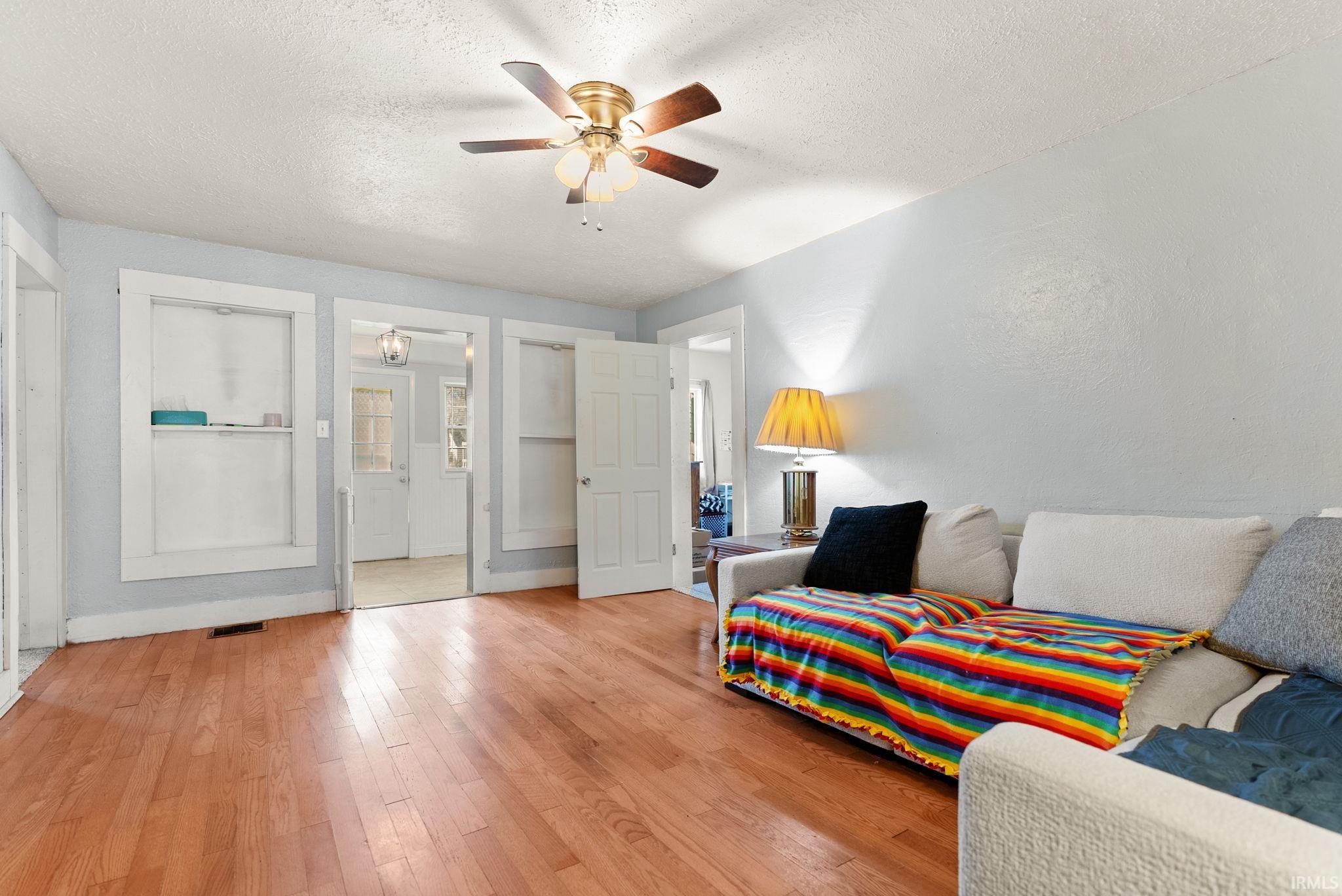 Sitting room with a textured ceiling, wood-type flooring, and a ceiling fan