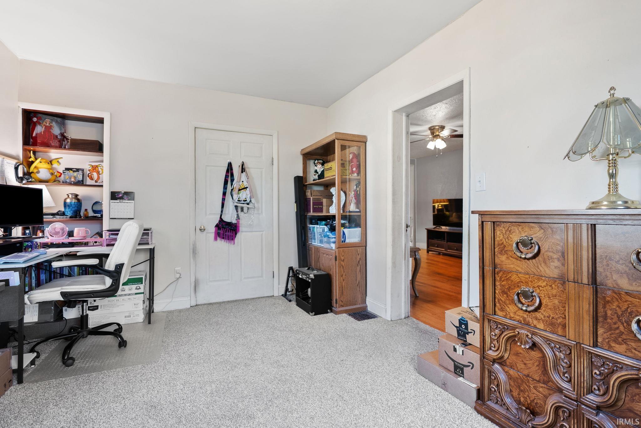 Office with light carpet and ceiling fan