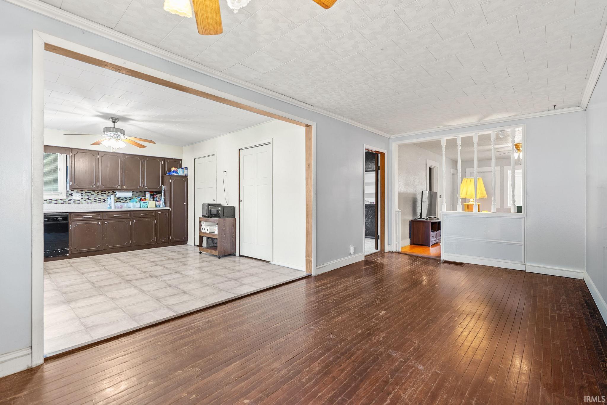 Unfurnished living room featuring ceiling fan, light wood-style floors, and crown molding