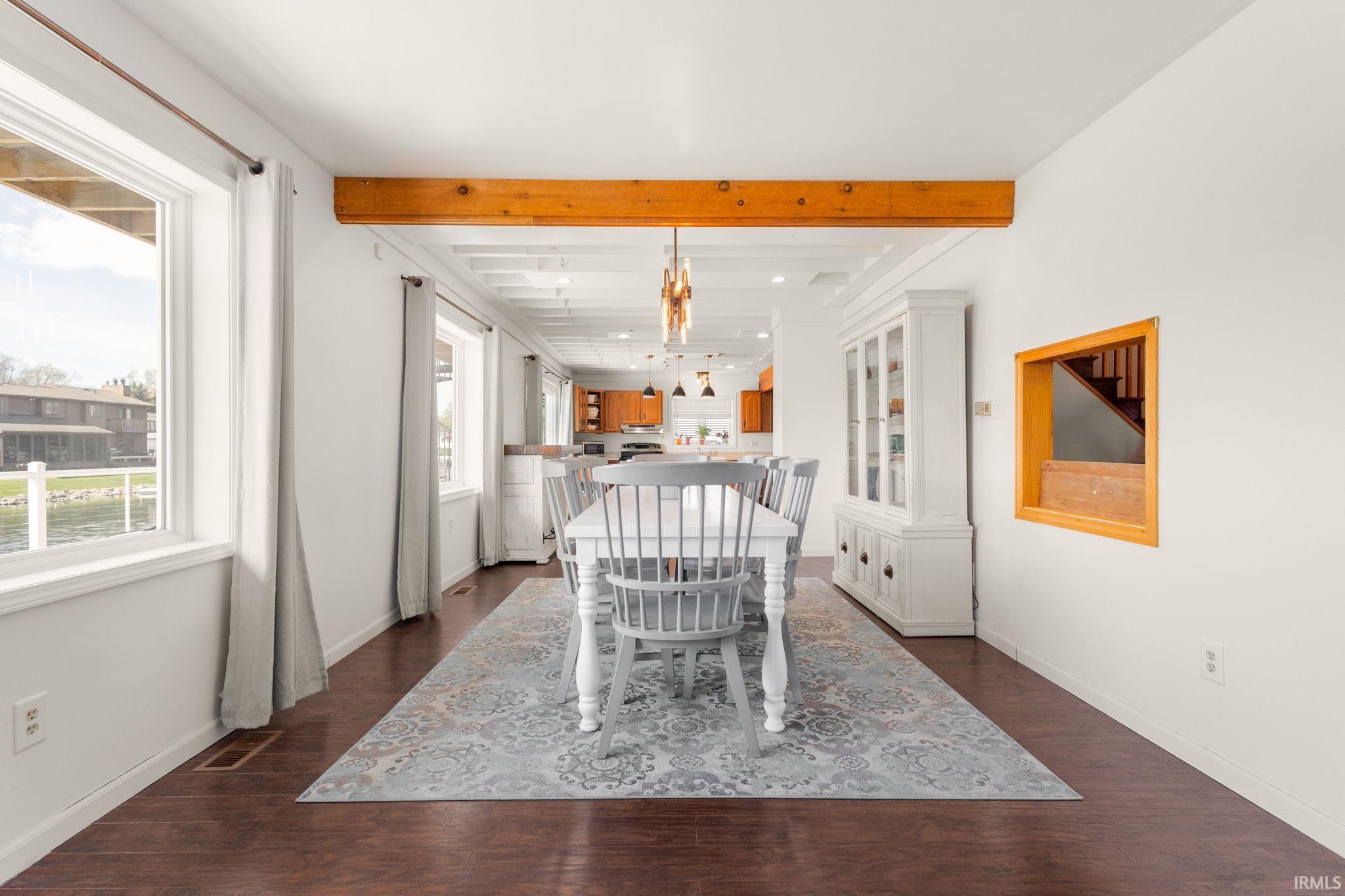 Dining area featuring dark wood finished floors and beam ceiling
