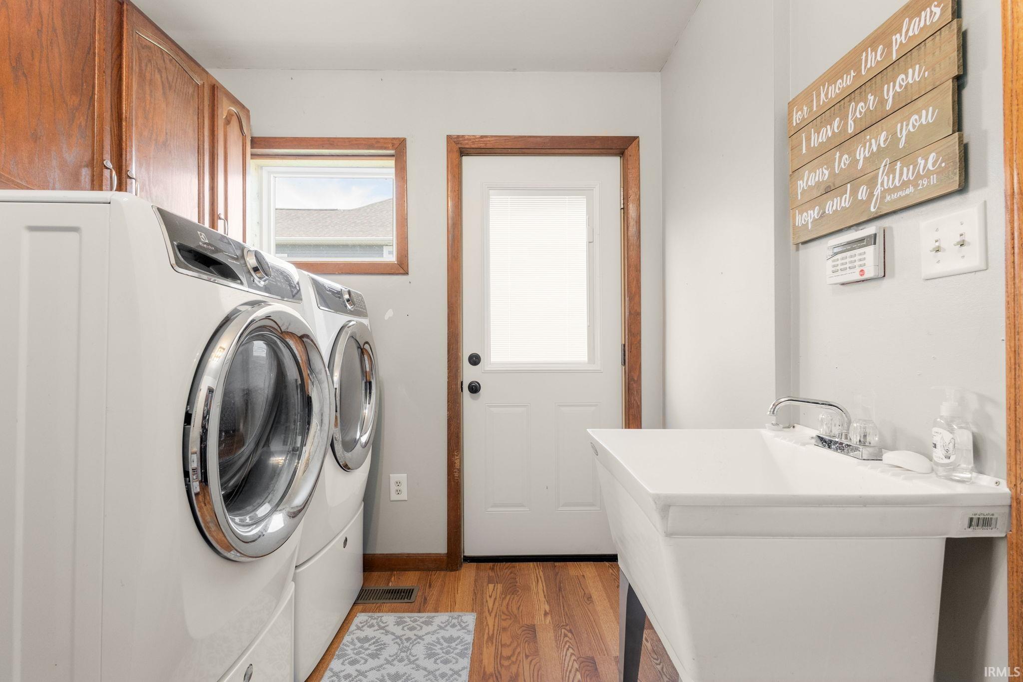 Laundry room with light wood-style flooring, washing machine and dryer, and cabinet space