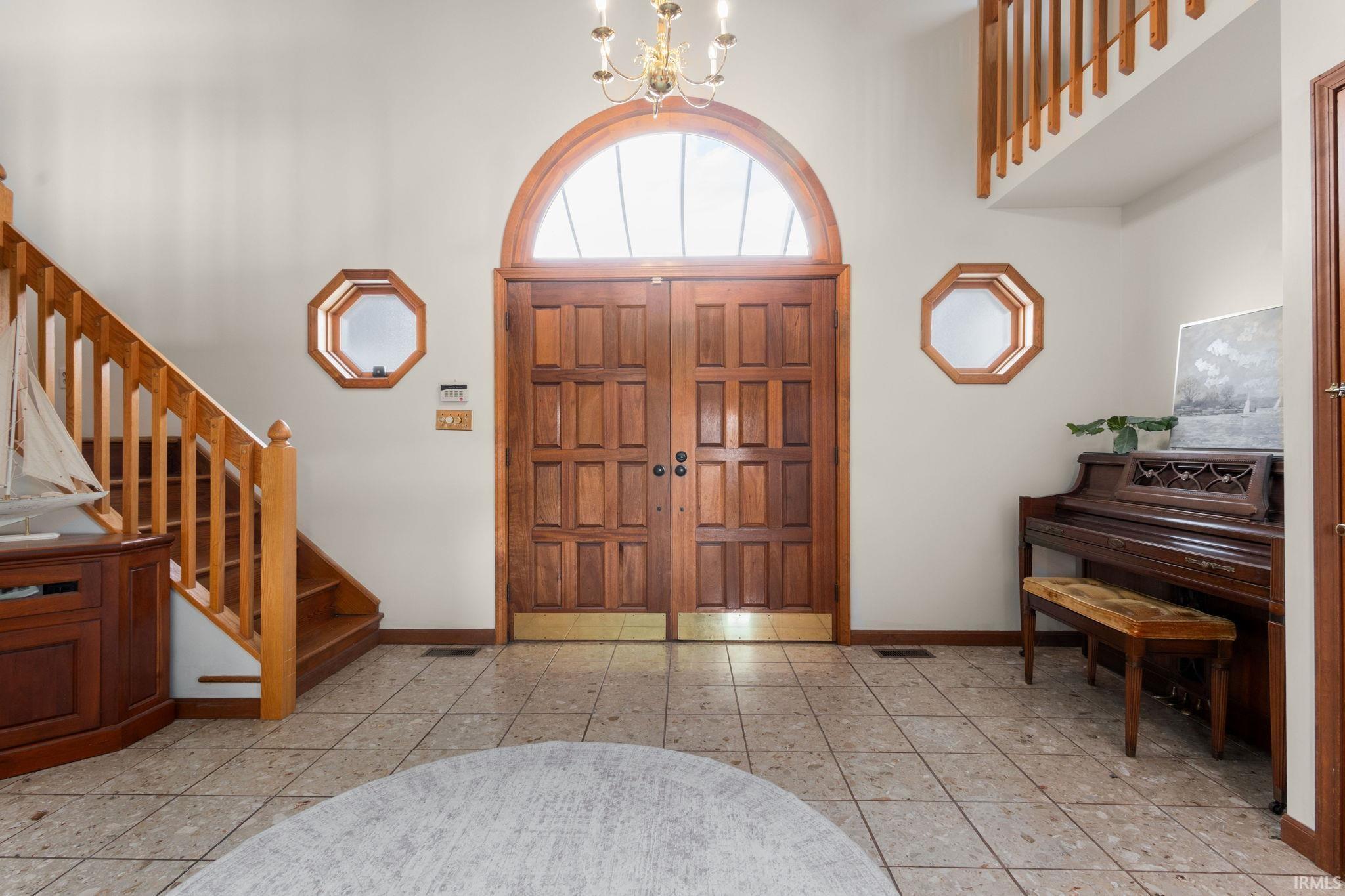 Entrance foyer featuring suspended lighting, a high ceiling, and light tile patterned flooring