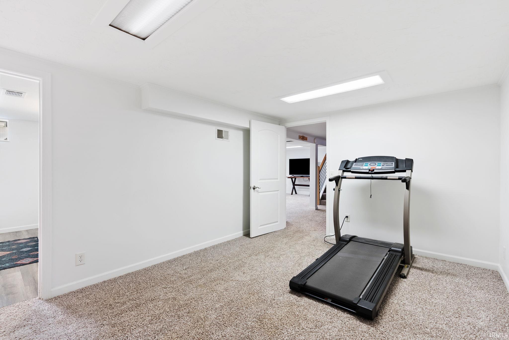 Workout area with baseboards and light carpet