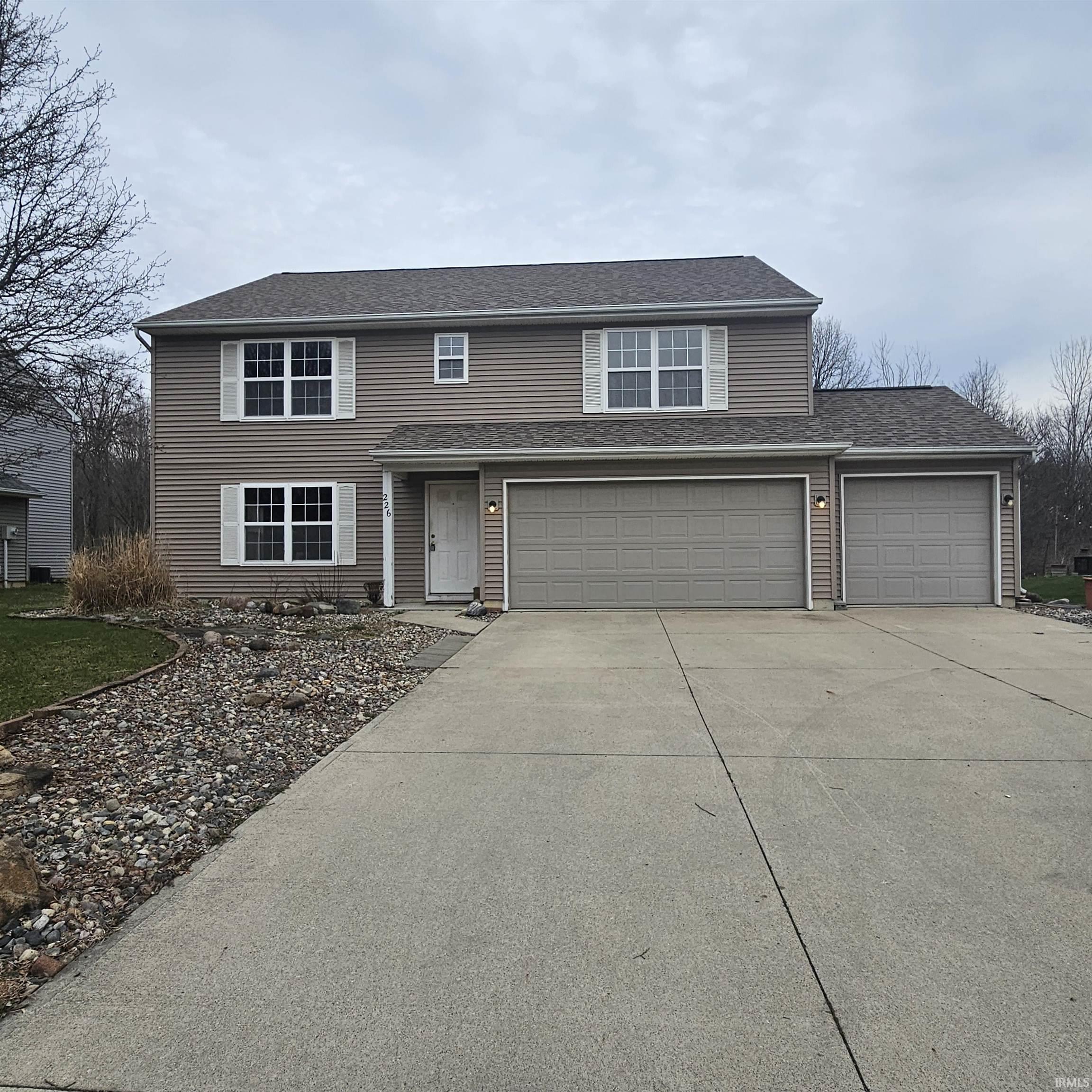 Traditional-style house featuring driveway, a shingled roof, and a garage