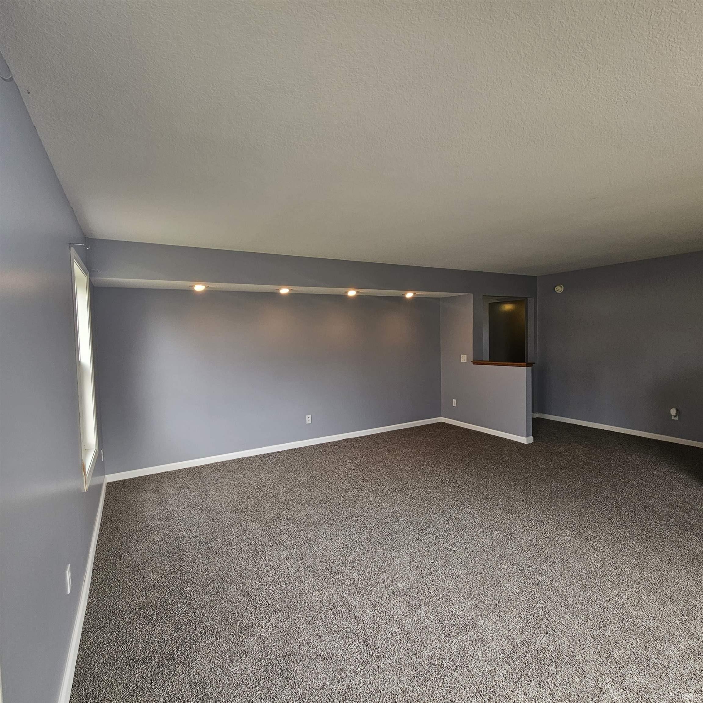 Spare room featuring dark carpet and a textured ceiling