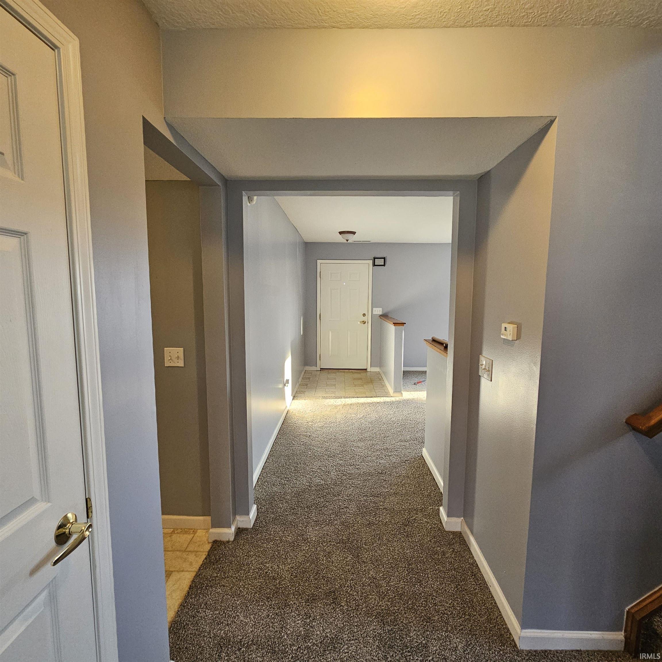Corridor featuring light colored carpet and baseboards