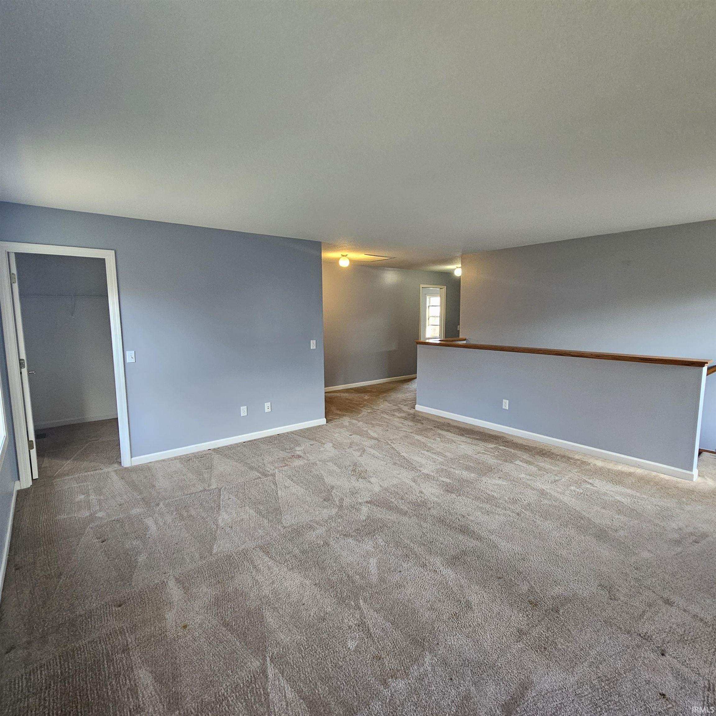 Empty room with light colored carpet and baseboards