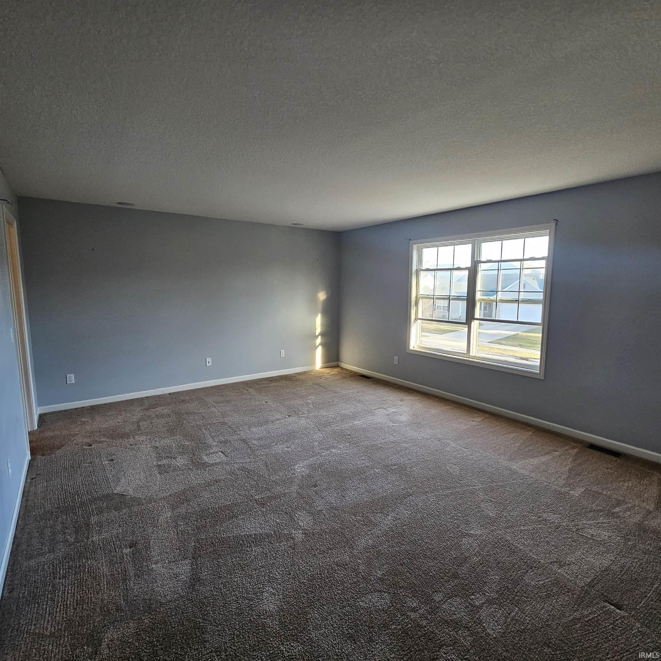 Empty room featuring a textured ceiling and dark carpet