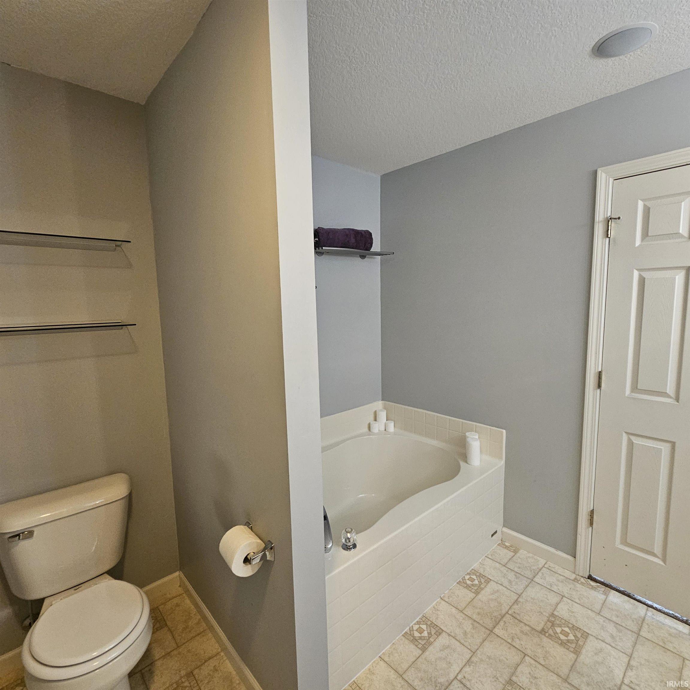 Bathroom with a bath and a textured ceiling