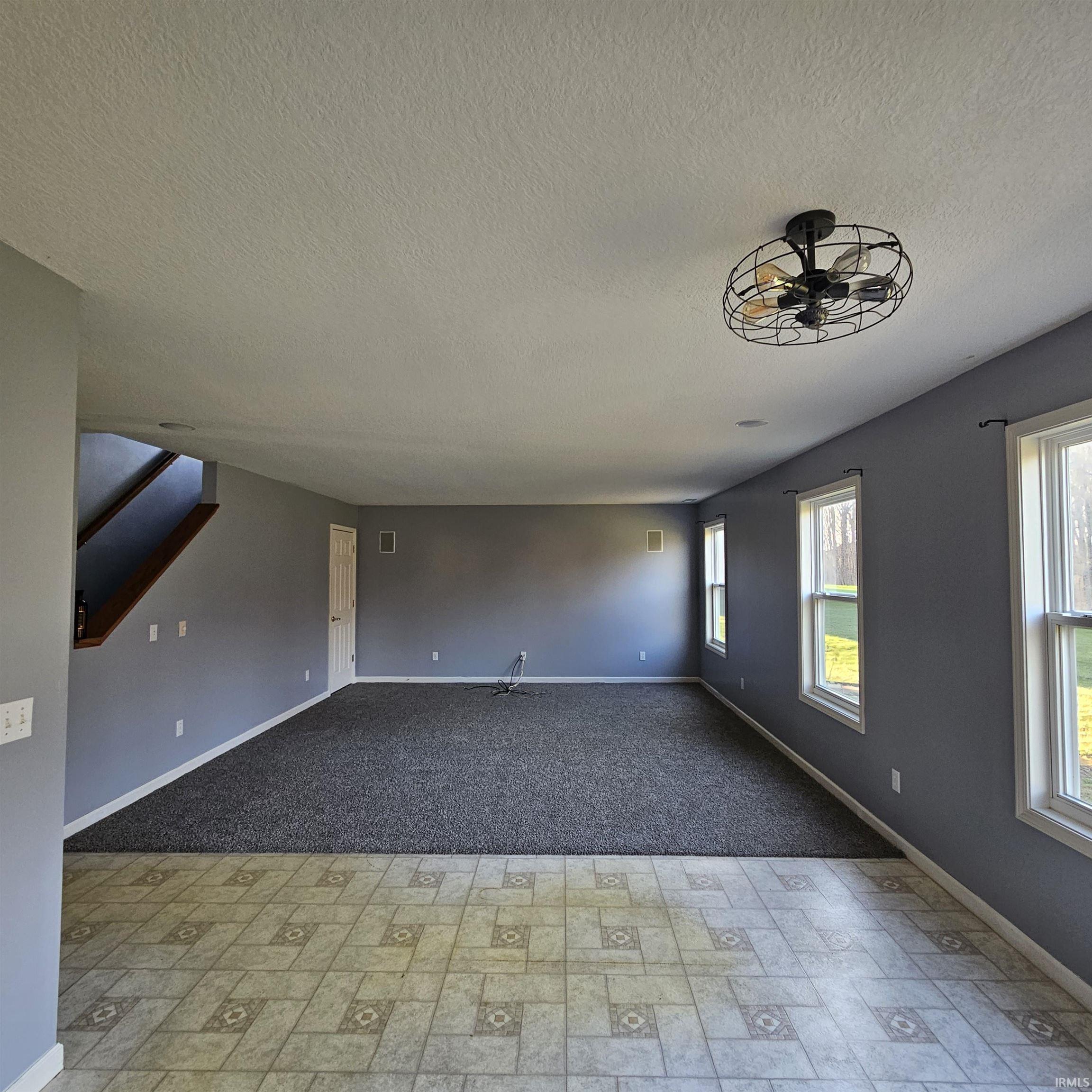 Unfurnished room with light colored carpet, a ceiling fan, and a textured ceiling