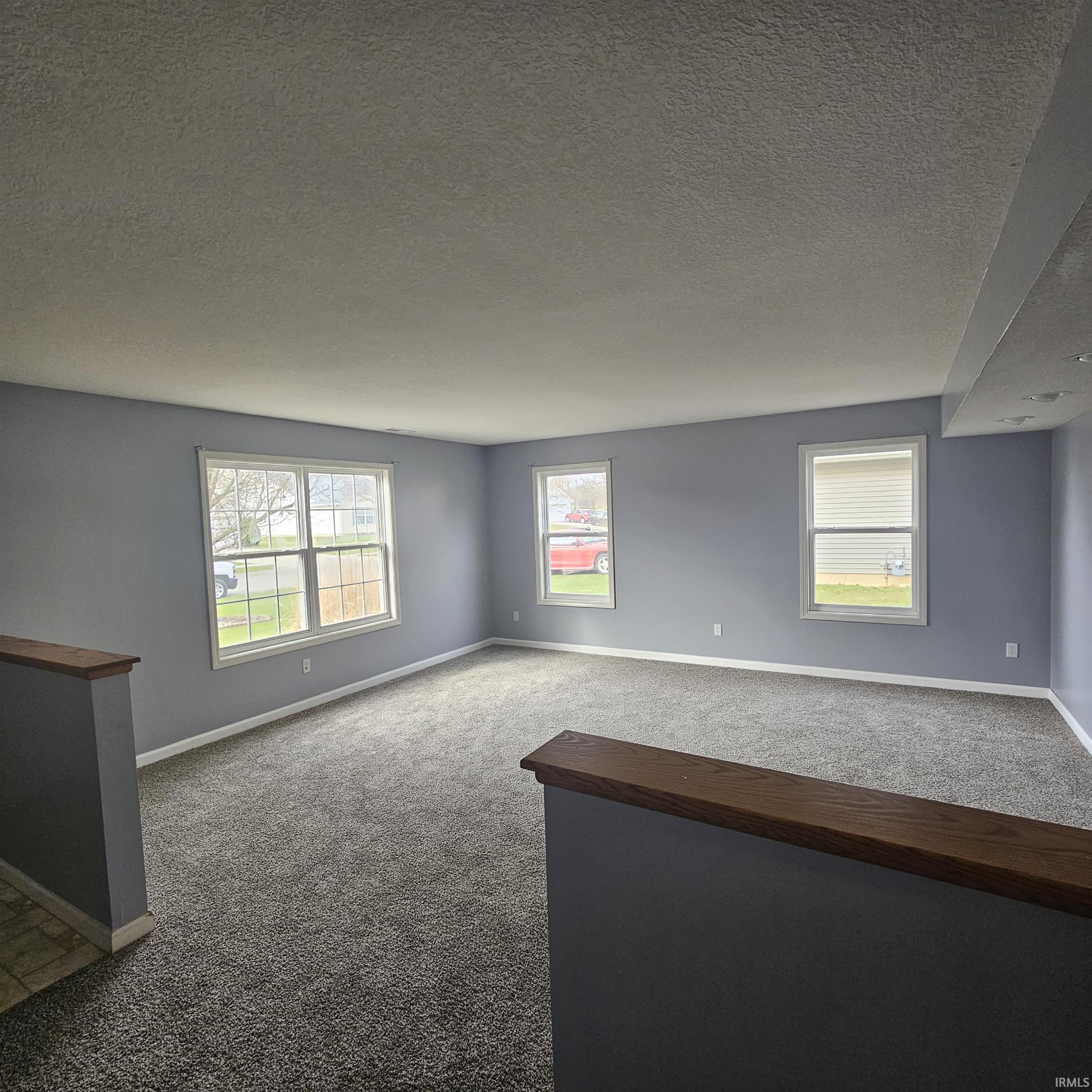 Carpeted empty room with baseboards and a textured ceiling