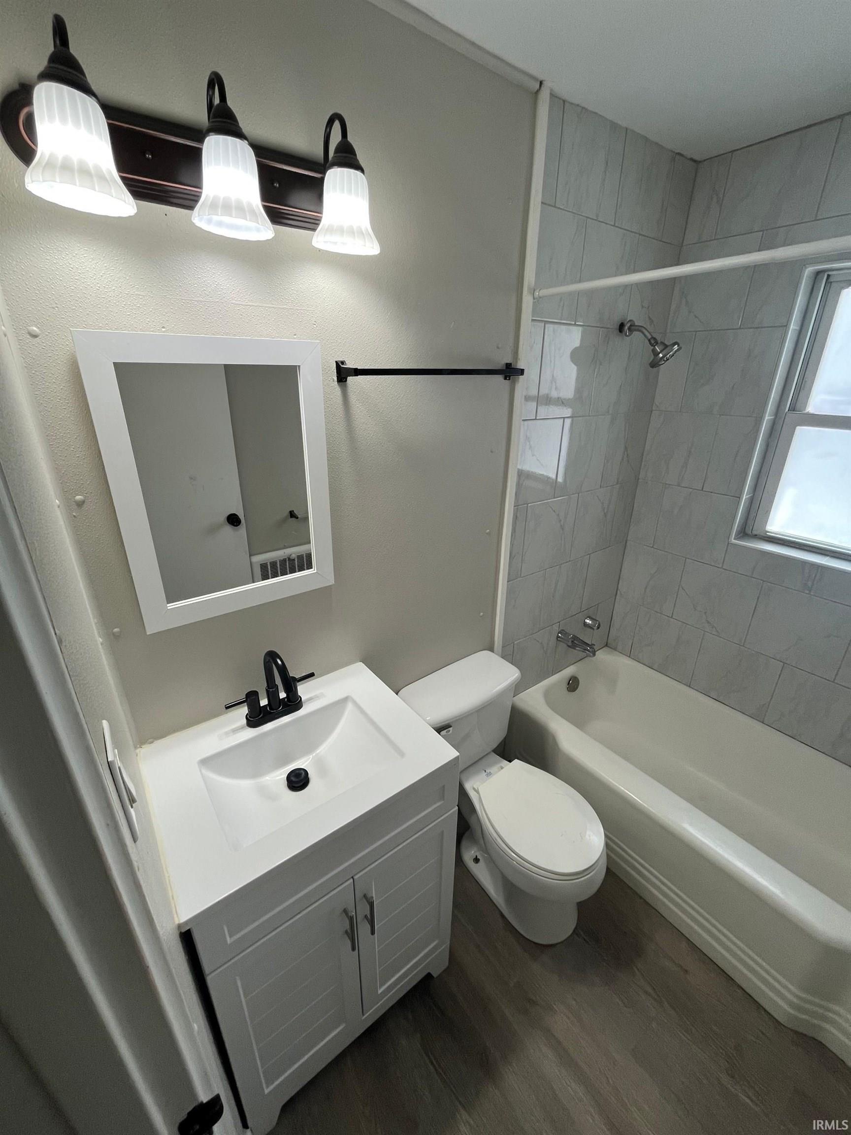 Bathroom featuring vanity, bathing tub / shower combination, and dark wood-style flooring