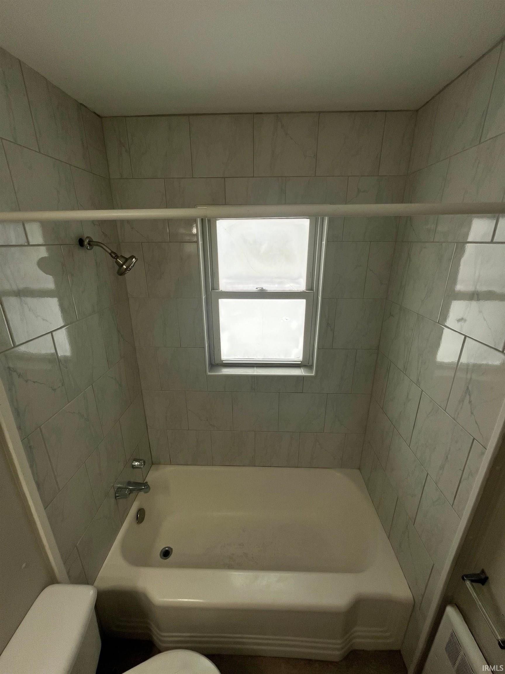 Bathroom featuring bathing tub / shower combination and radiator