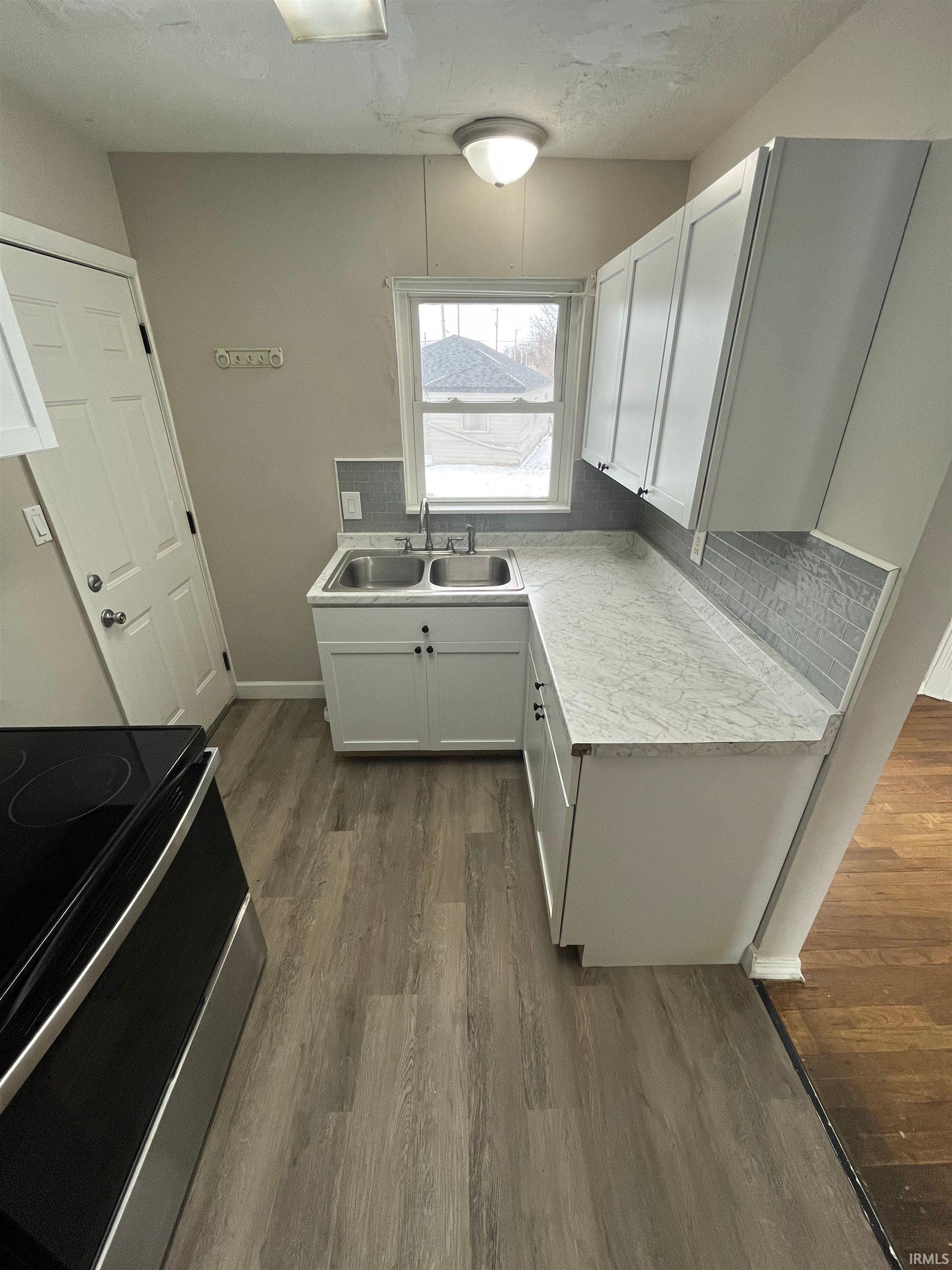 Kitchen with stainless steel electric range oven, light countertops, tasteful backsplash, and white cabinets