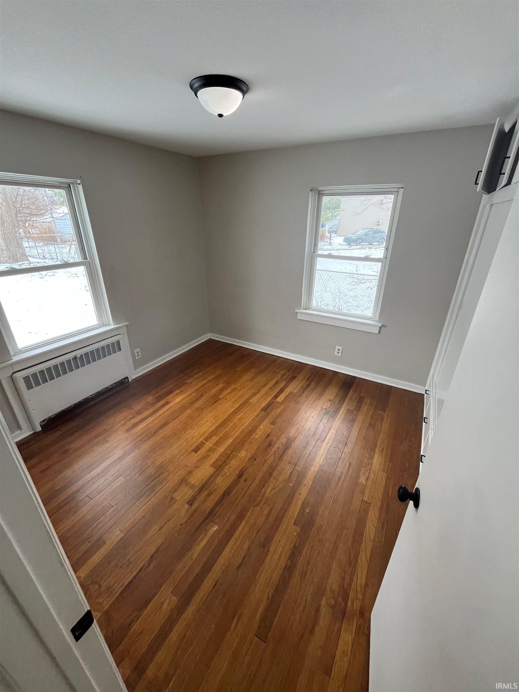Unfurnished room with dark wood-type flooring and radiator heating unit