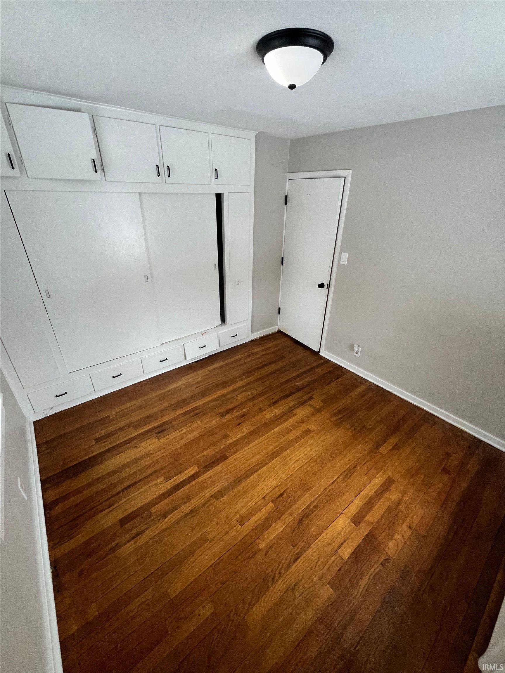 Unfurnished bedroom with dark wood-style flooring and a closet