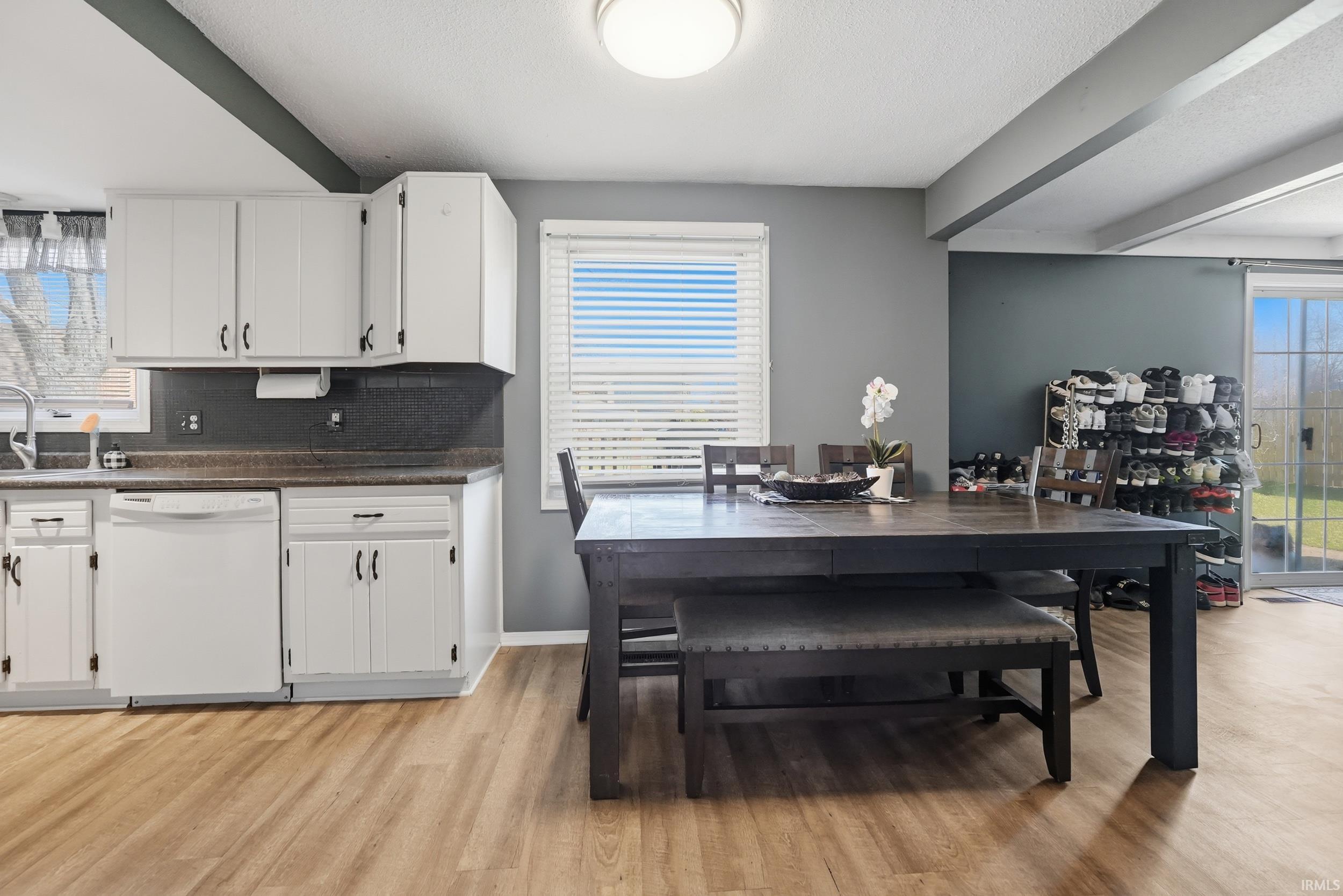 Dining room featuring light wood-style floors, beamed ceiling, and a textured ceiling