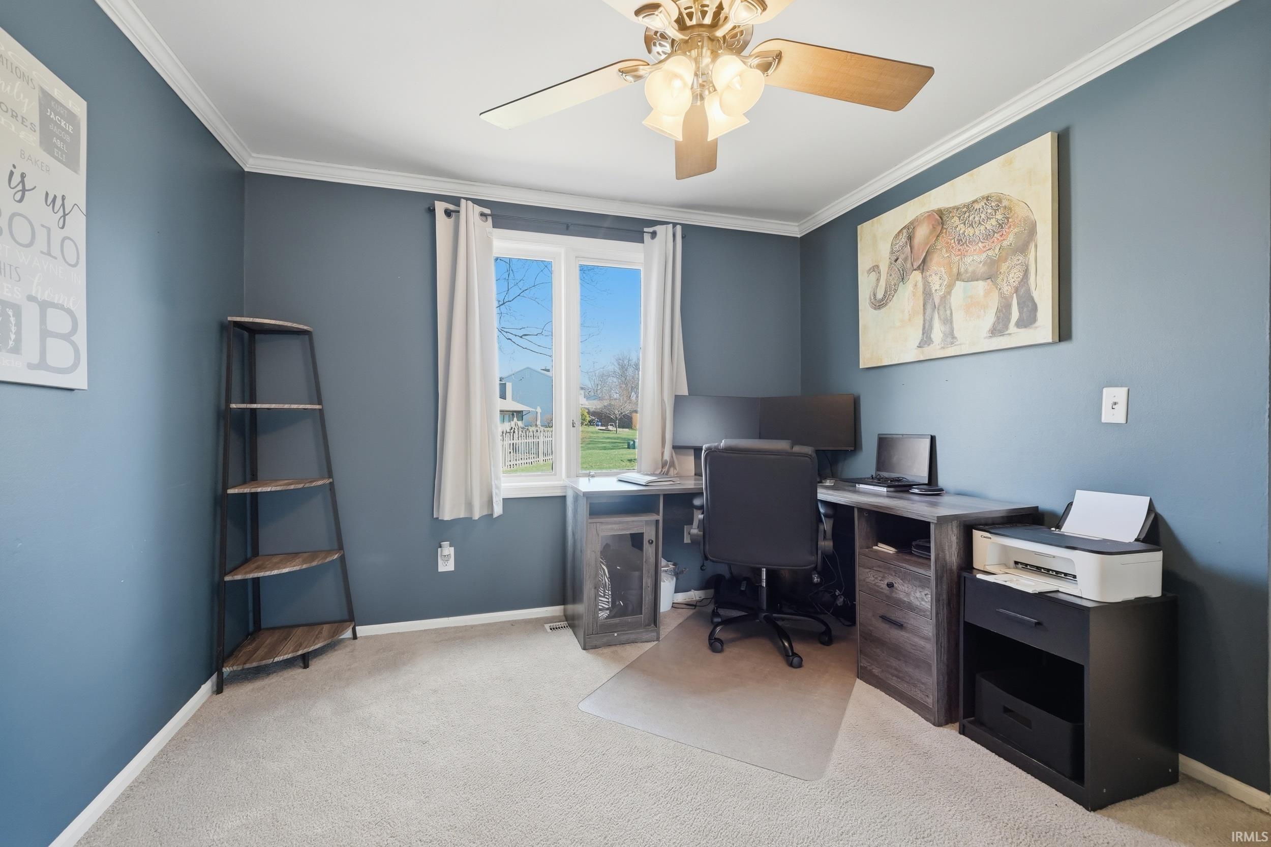 Home office featuring light colored carpet, ornamental molding, and a ceiling fan