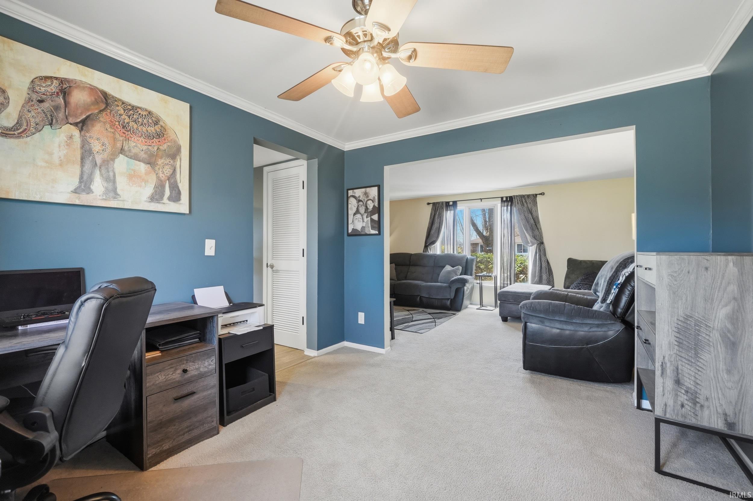 Office space with light carpet, ornamental molding, and a ceiling fan
