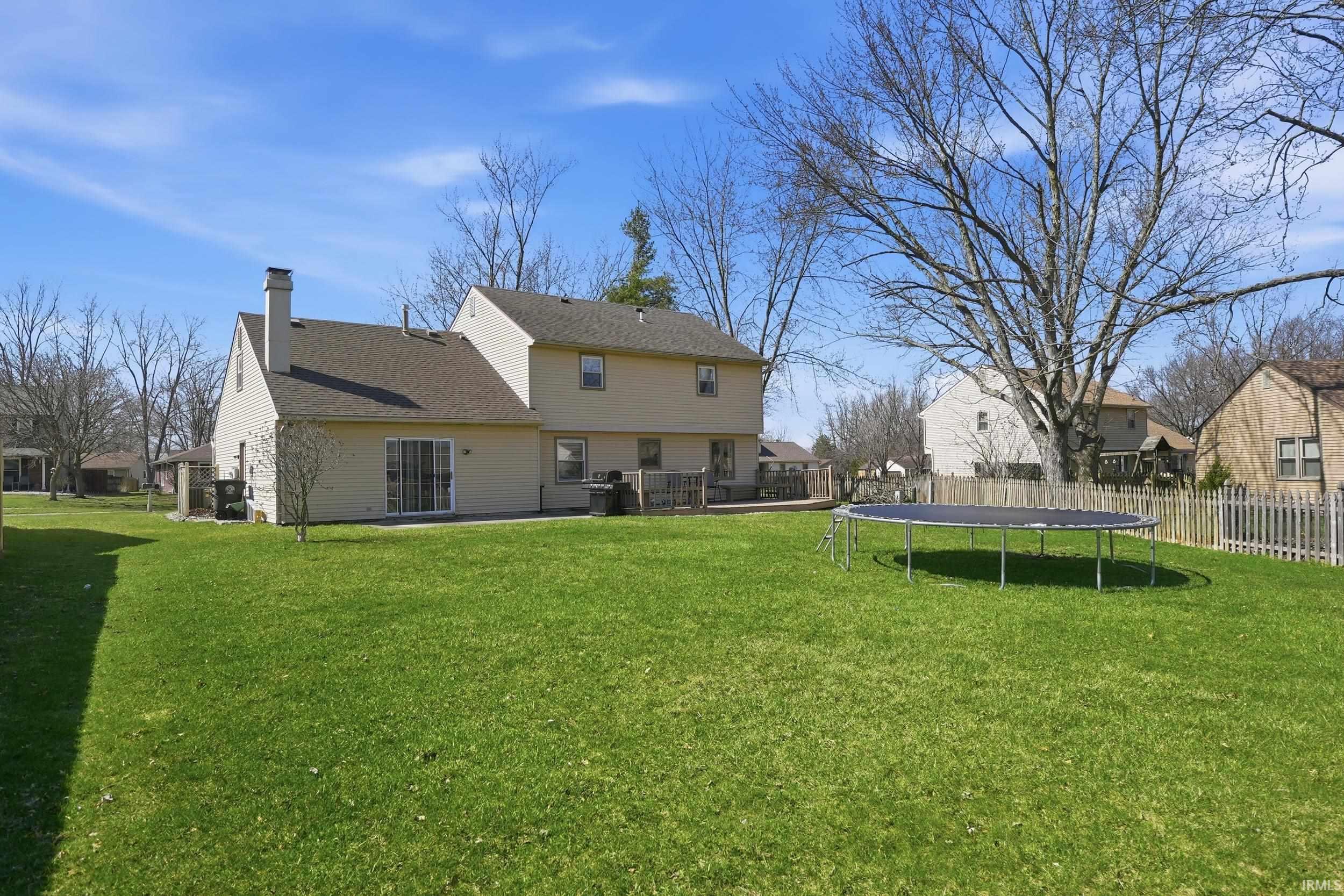Rear view of property with a trampoline, a chimney, roof with shingles, a residential view, and a patio area