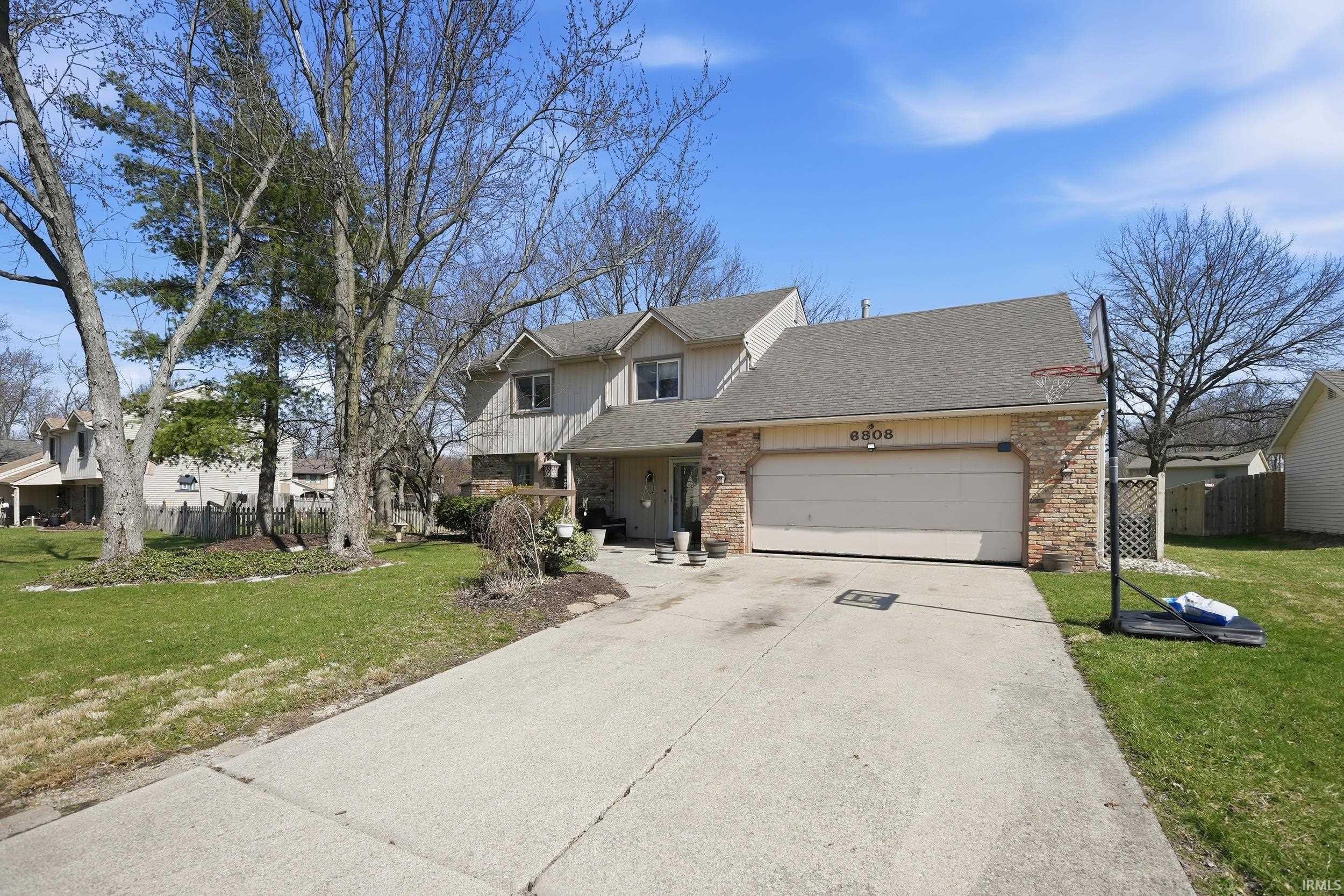 Traditional home with a garage, brick siding, a shingled roof, concrete driveway, and covered porch