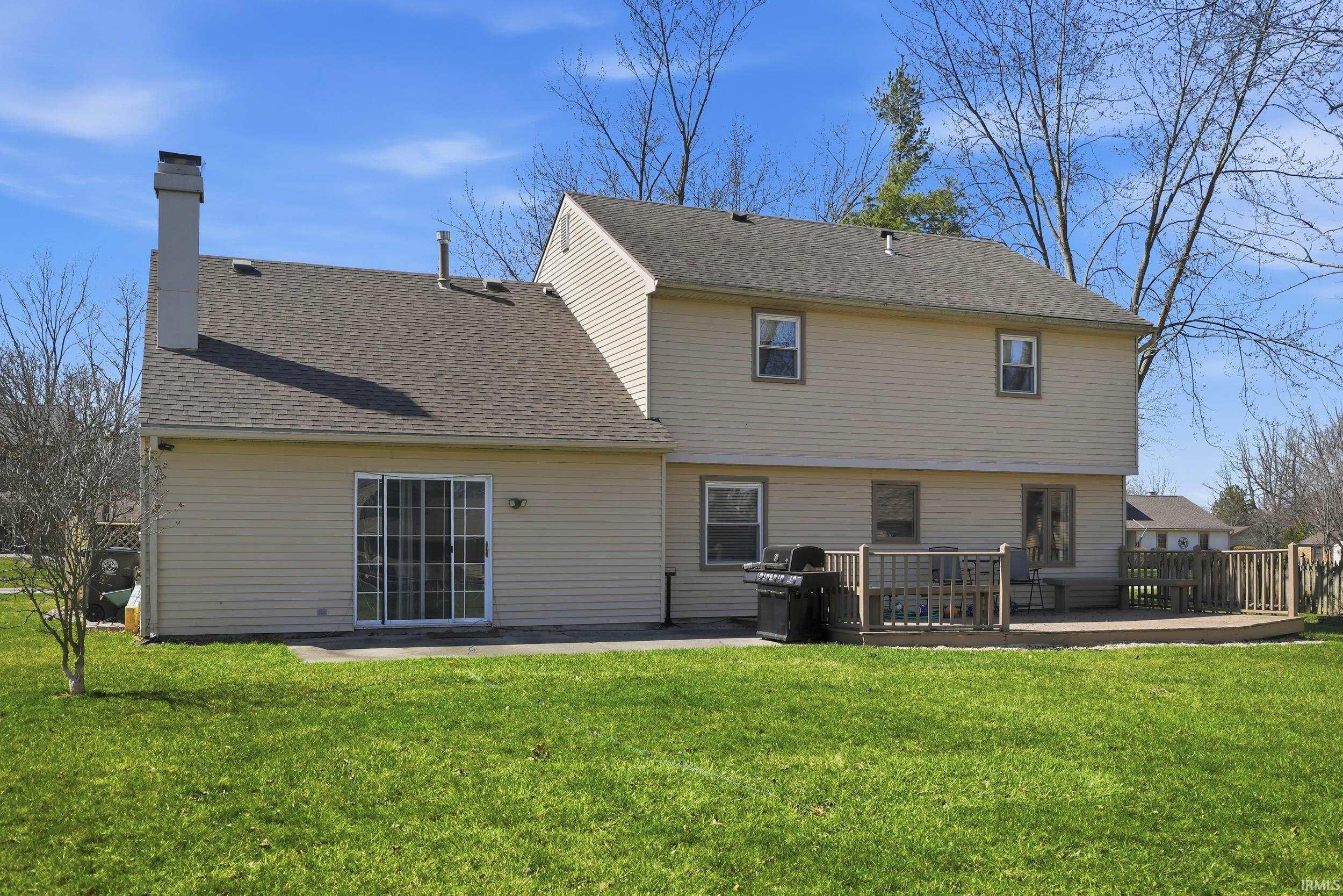 Back of house with a chimney, a lawn, a shingled roof, and a wooden deck