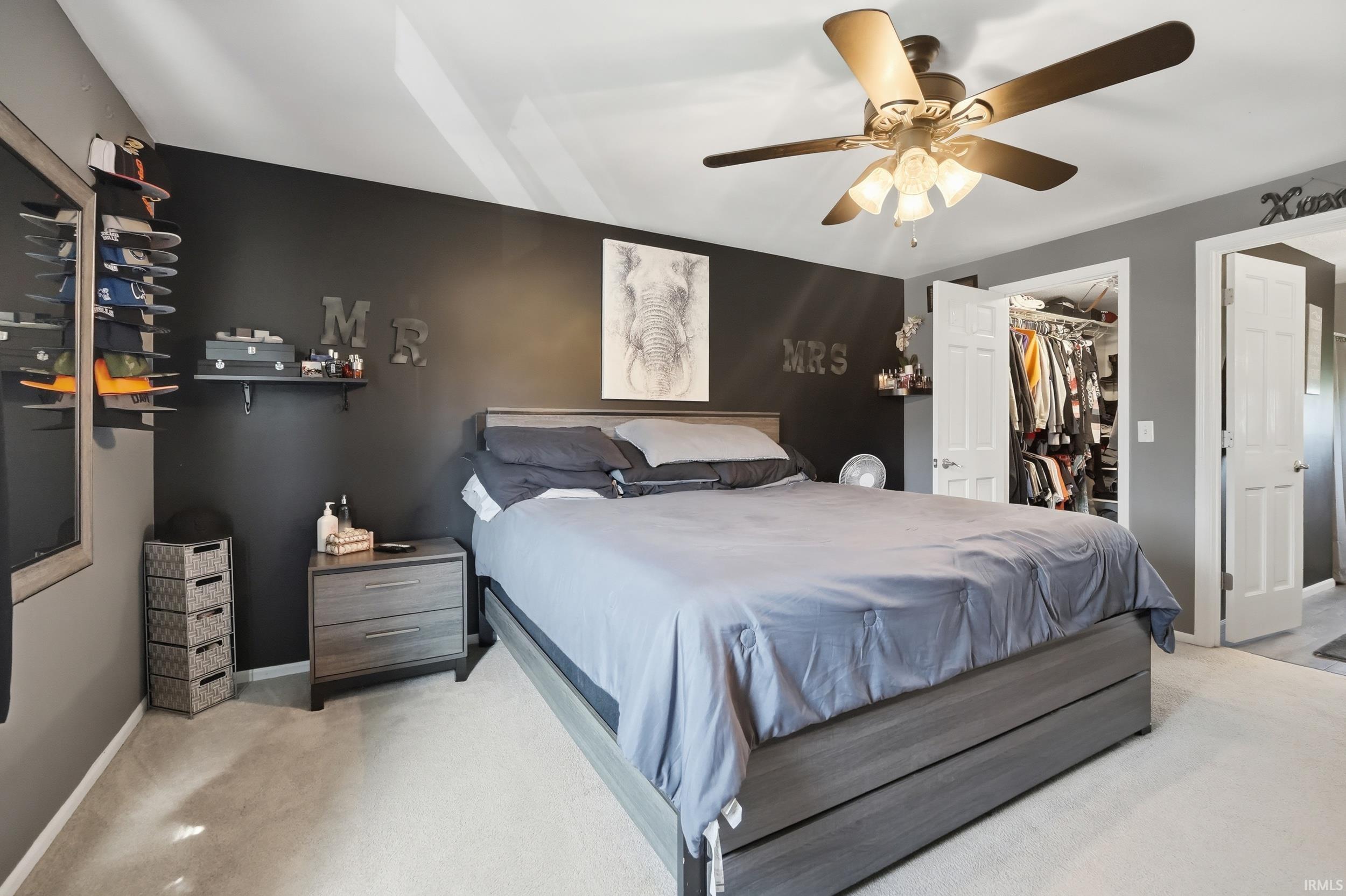 Bedroom featuring light carpet, a walk in closet, and ceiling fan