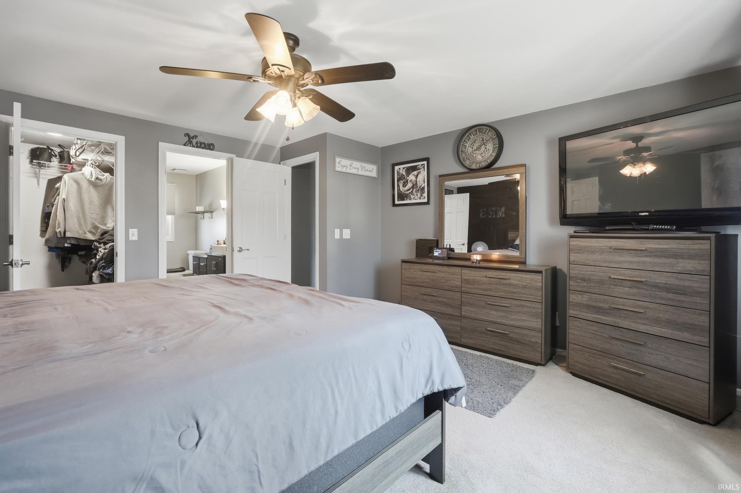 Bedroom featuring light colored carpet, ceiling fan, a spacious closet, and ensuite bath
