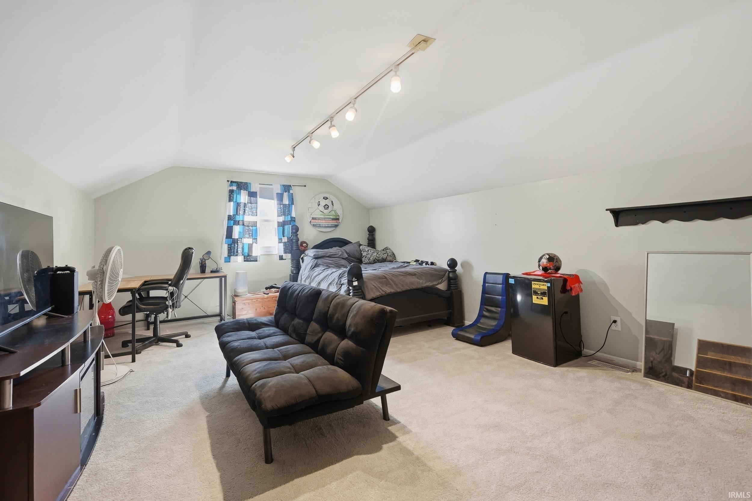Bedroom featuring light carpet, an office area, and track lighting