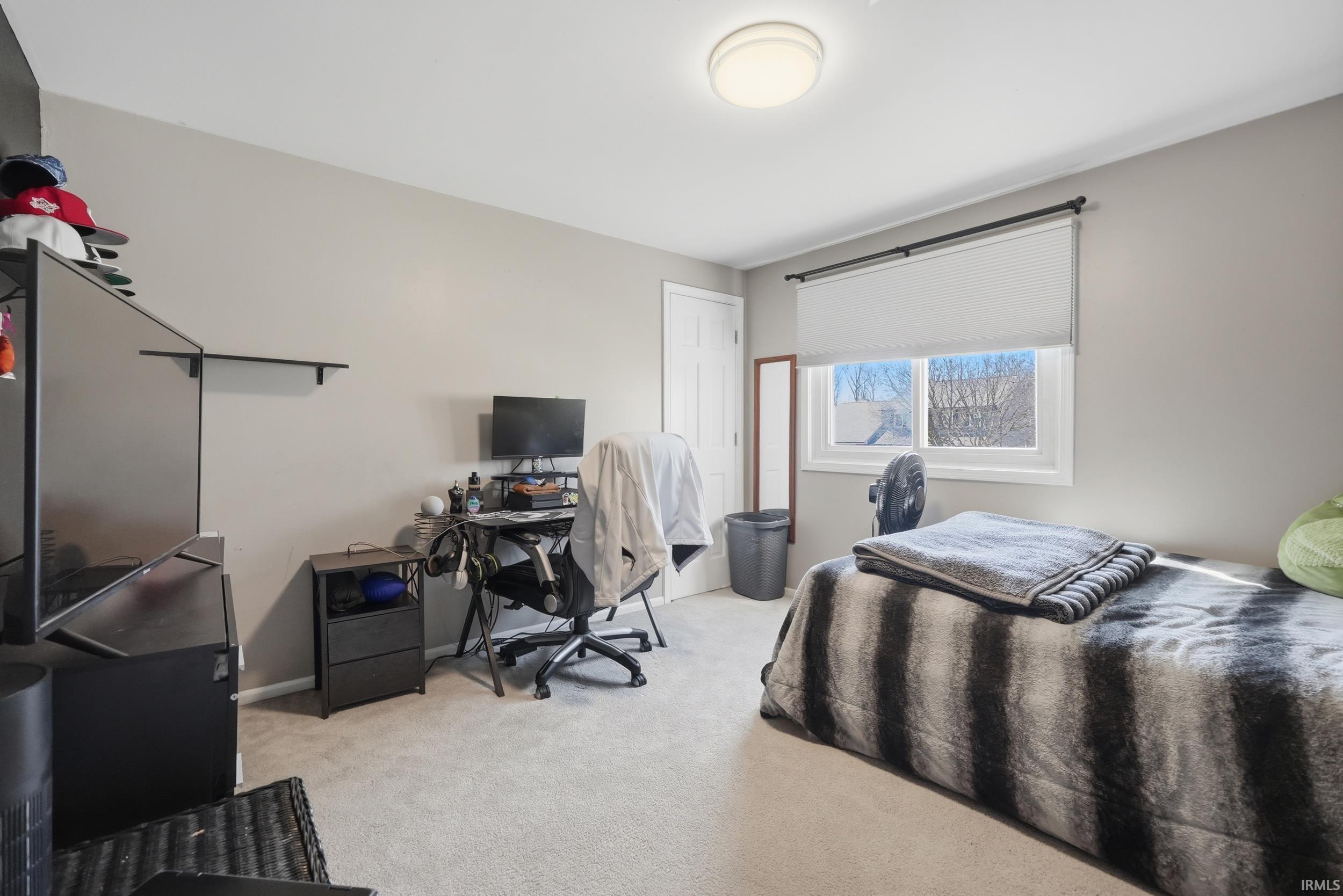 Bedroom featuring light carpet and a desk