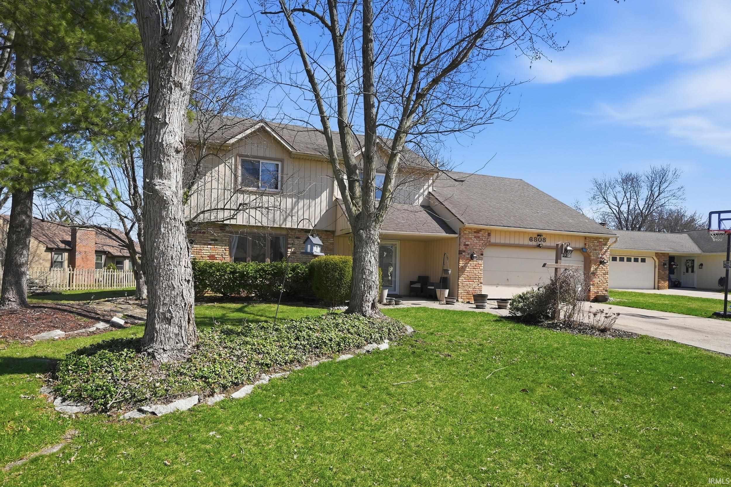 View of front of house with brick siding, an attached garage, a patio area, a front yard, and a shingled roof