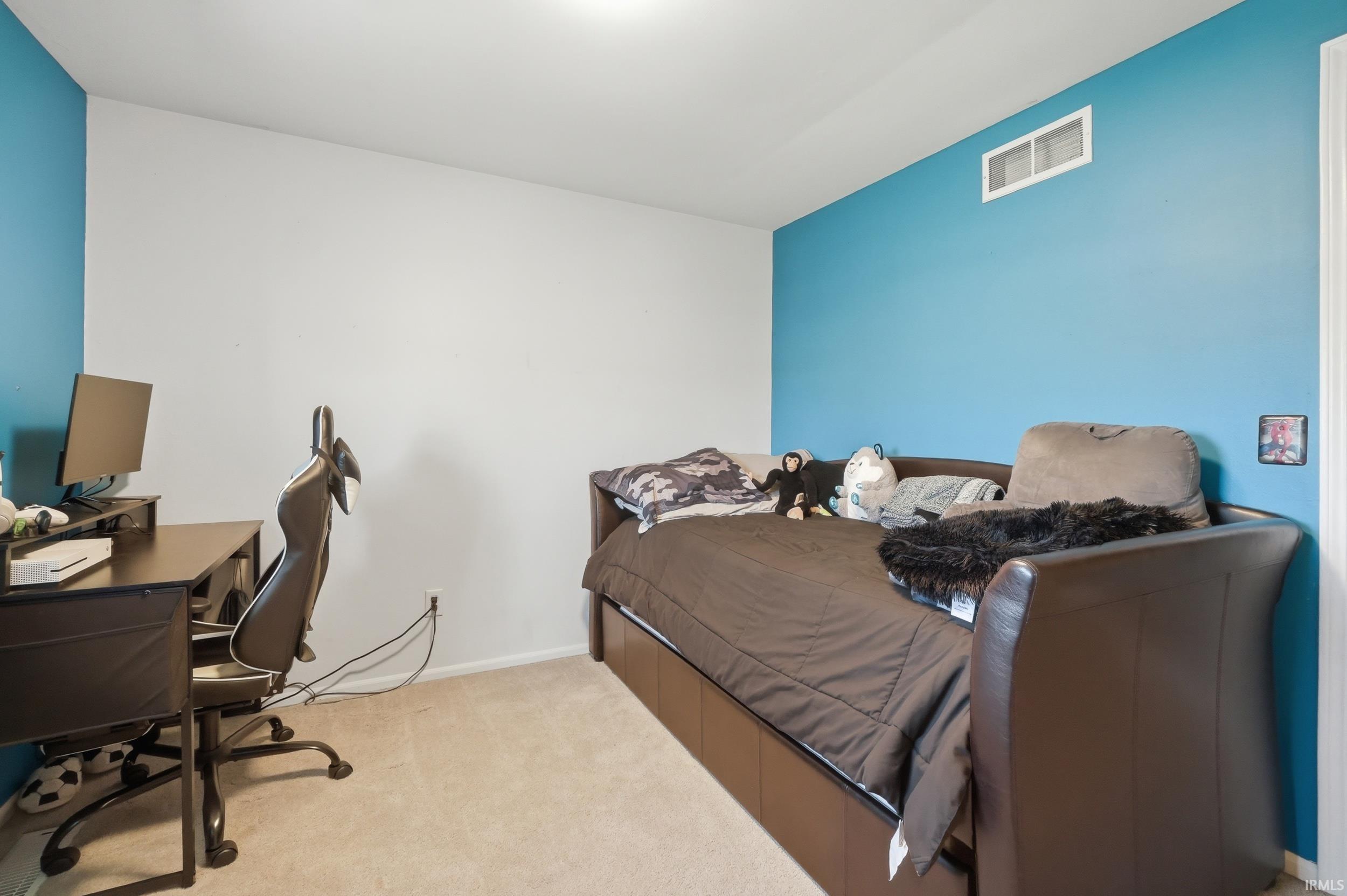 Bedroom featuring an office area and light colored carpet