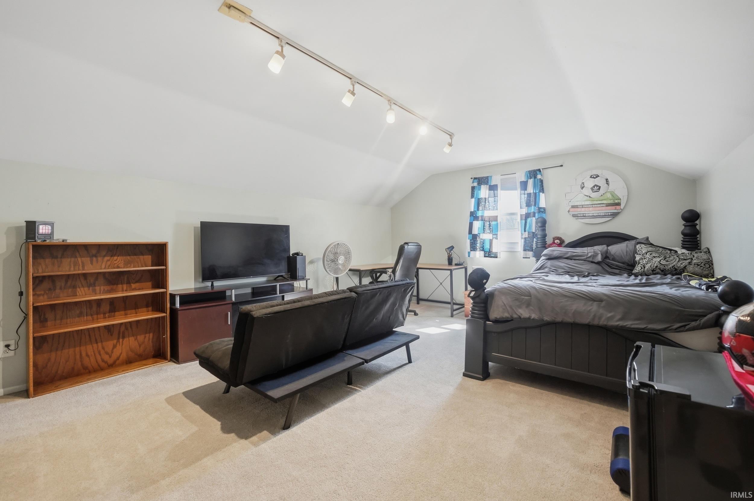 Bedroom with light colored carpet and track lighting