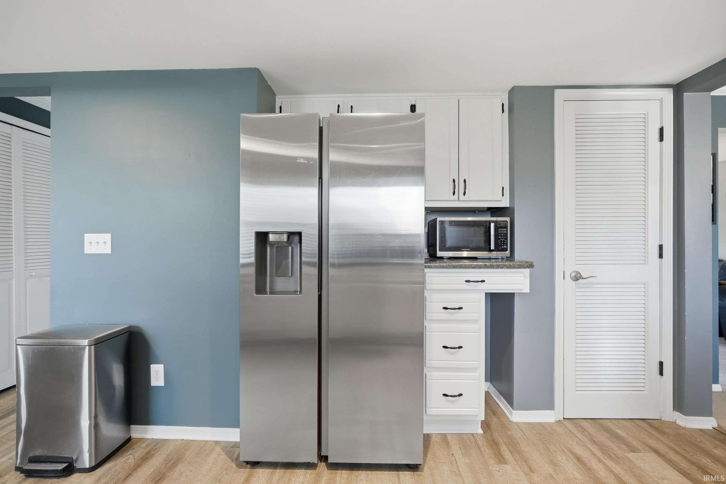 Kitchen with stainless steel appliances, white cabinetry, and light wood-type flooring