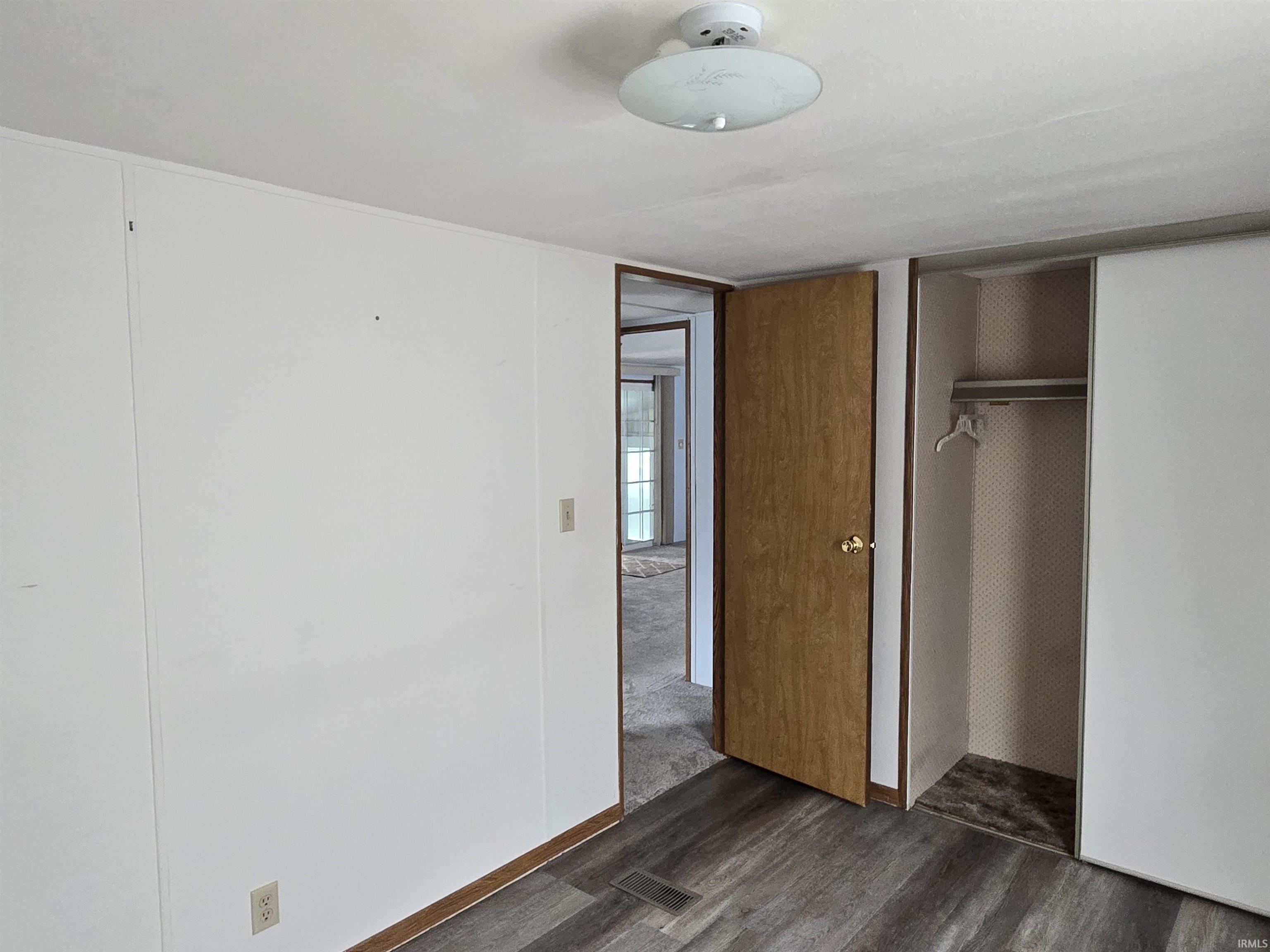 Unfurnished bedroom with dark wood-style floors and a closet