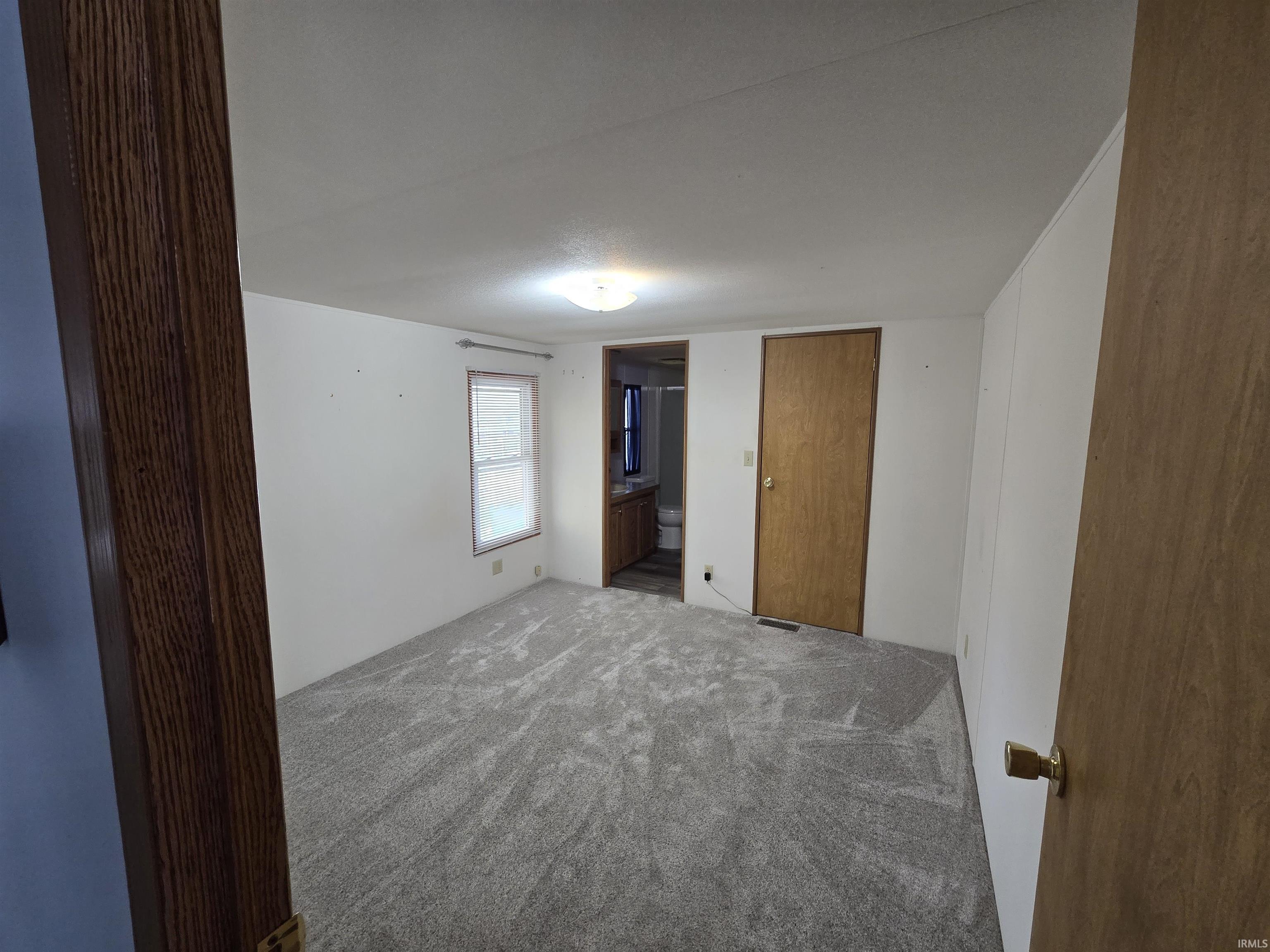 Unfurnished bedroom featuring carpet floors and connected bathroom