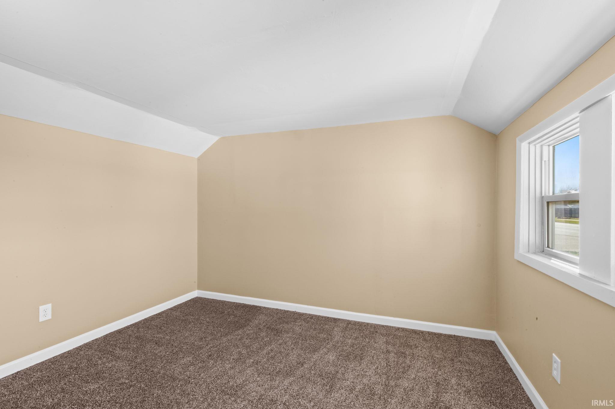Additional living space featuring lofted ceiling and dark carpet