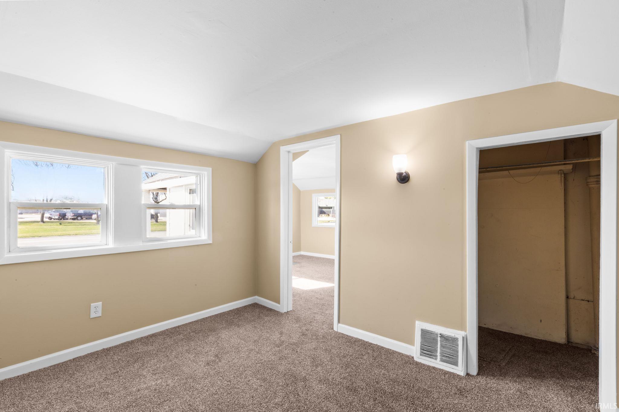 Unfurnished bedroom featuring lofted ceiling, carpet floors, and a closet