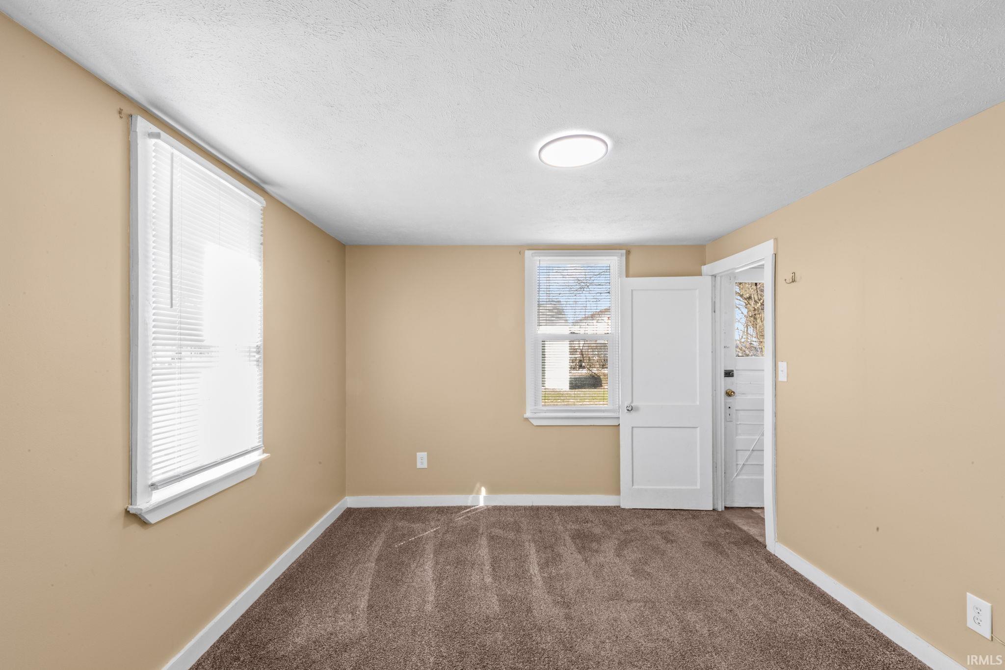 Empty room with dark carpet and a textured ceiling