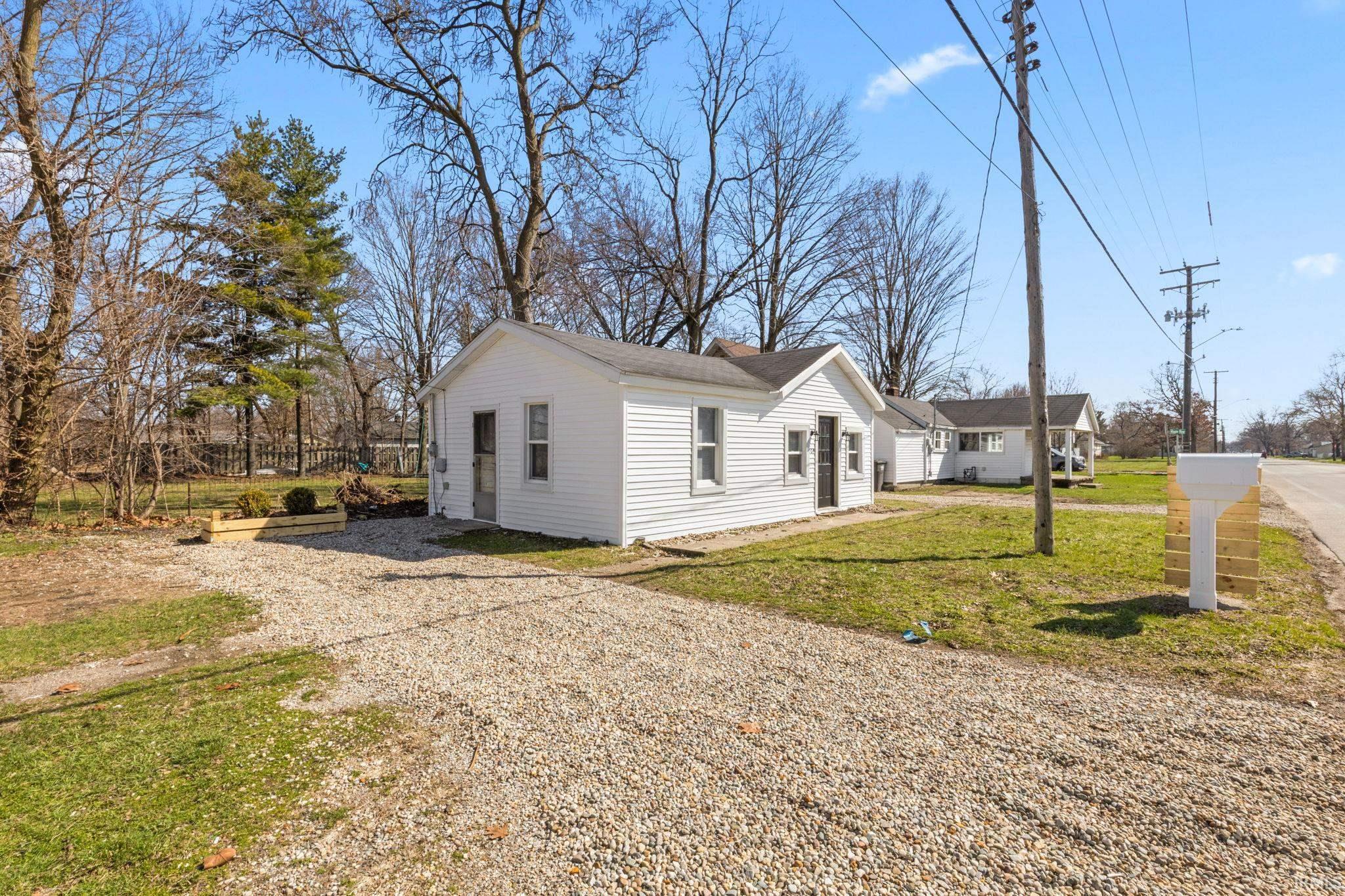 View of front of house featuring a shingled roof, driveway, and a front lawn