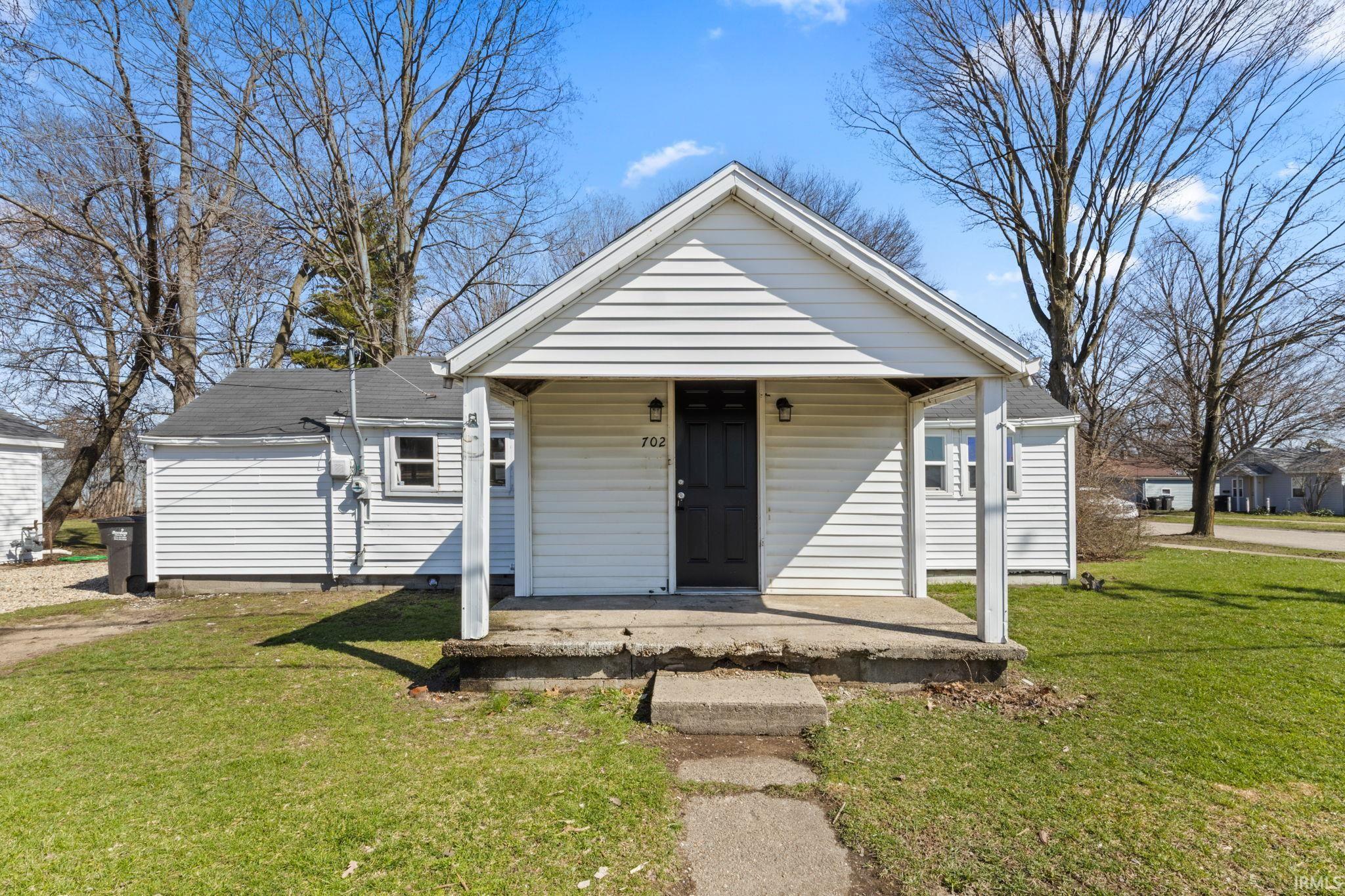 Bungalow featuring covered porch and a front yard