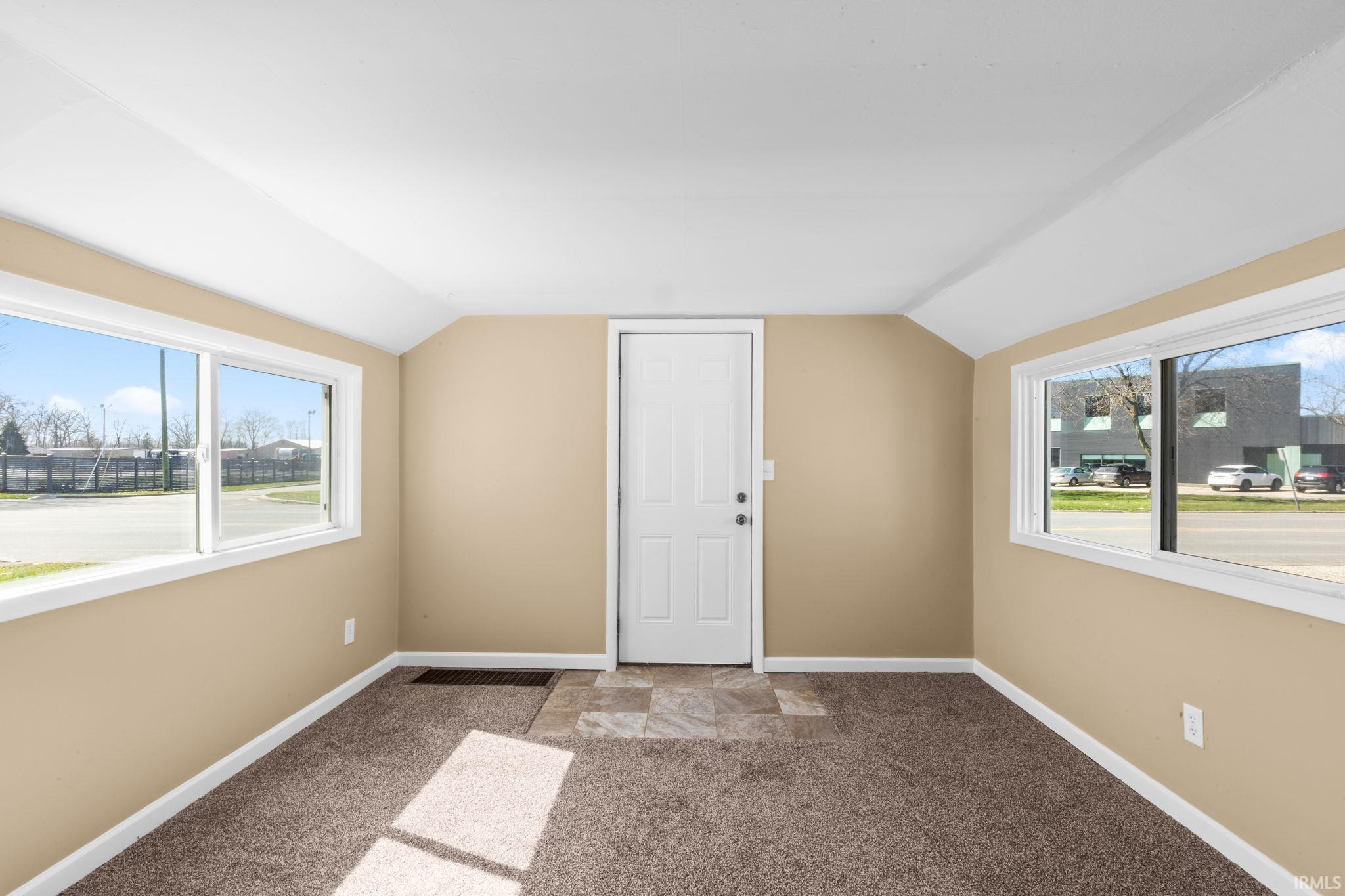 Additional living space featuring vaulted ceiling, plenty of natural light, and light colored carpet