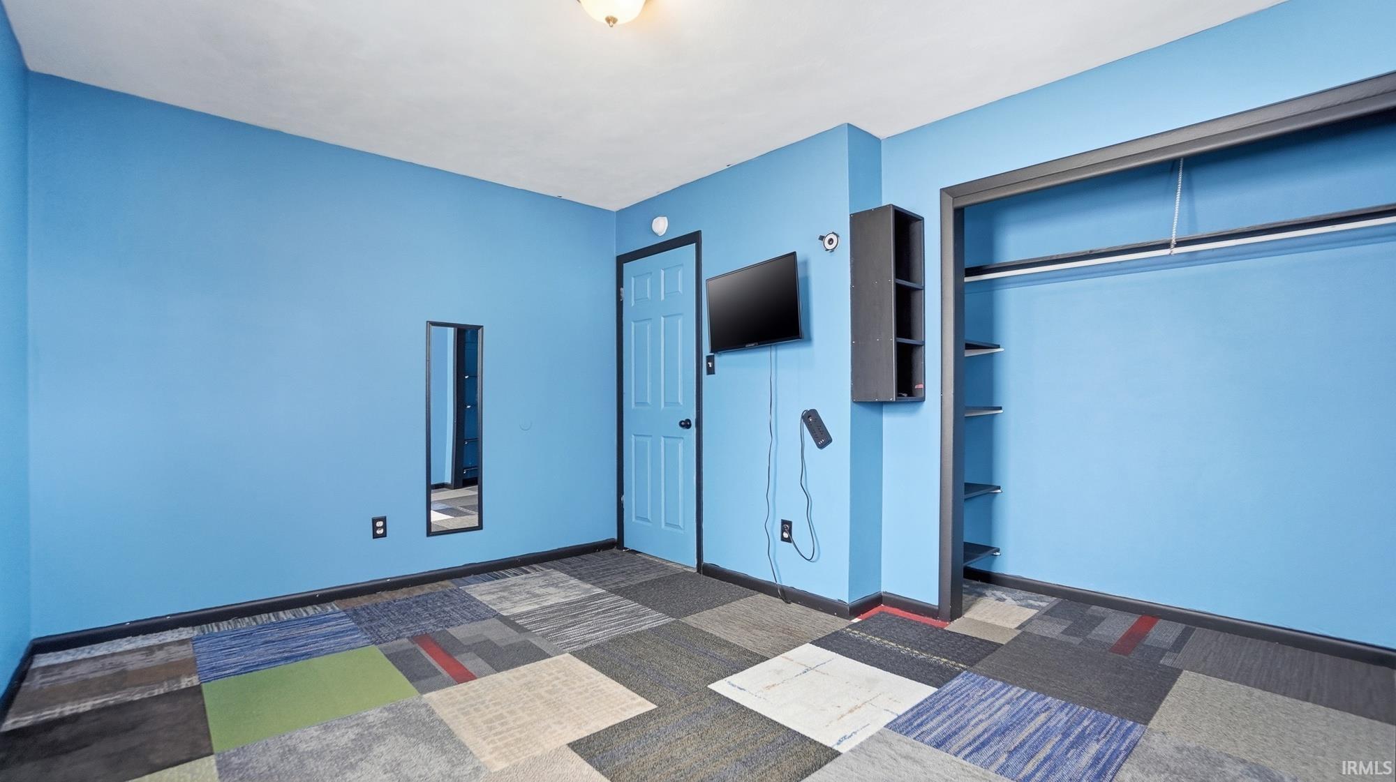 Unfurnished bedroom featuring a closet and dark carpet