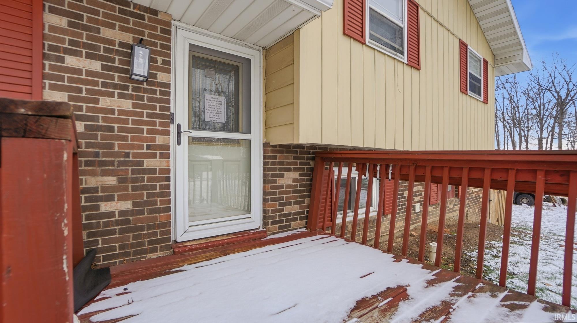 Snow covered property entrance with brick siding