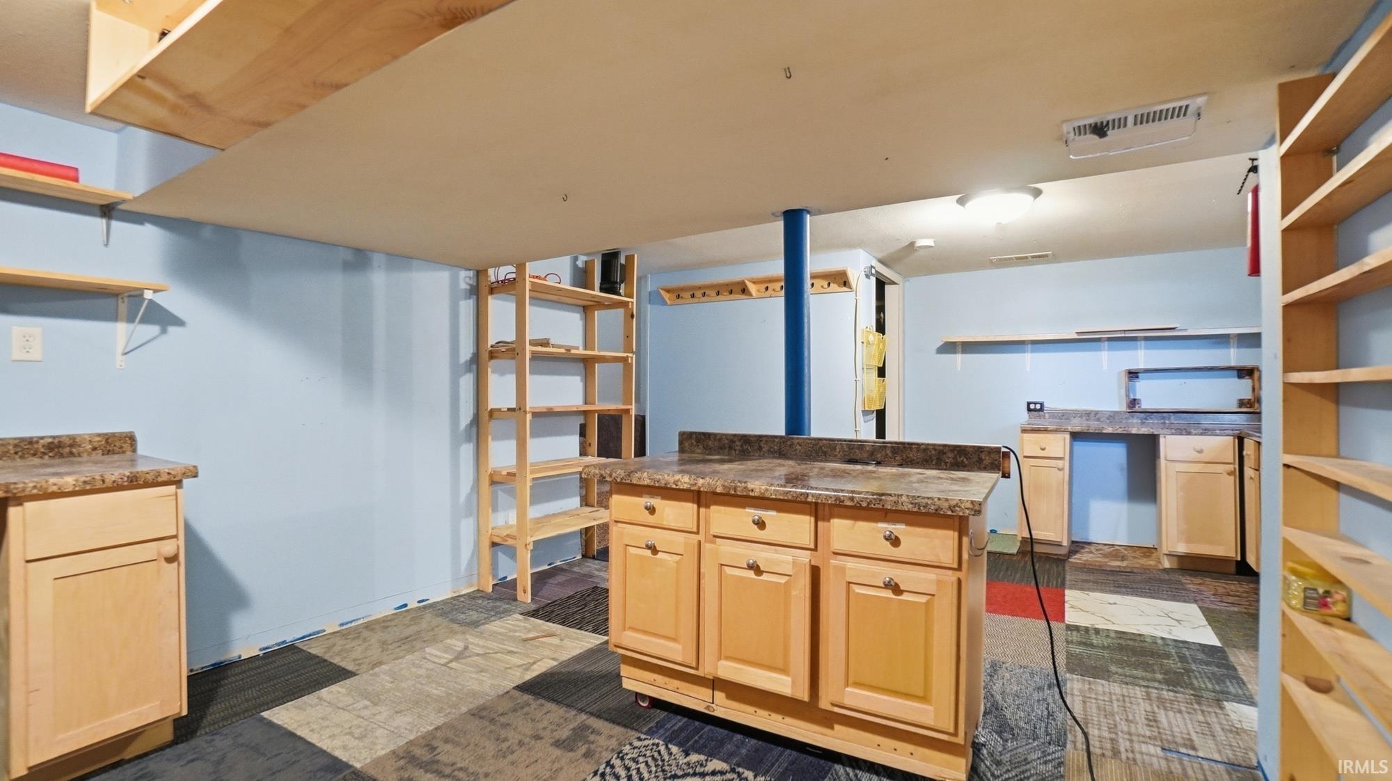 Kitchen featuring open shelves, light wood finish cabinetry, dark countertops, refrigerator, and a kitchen island