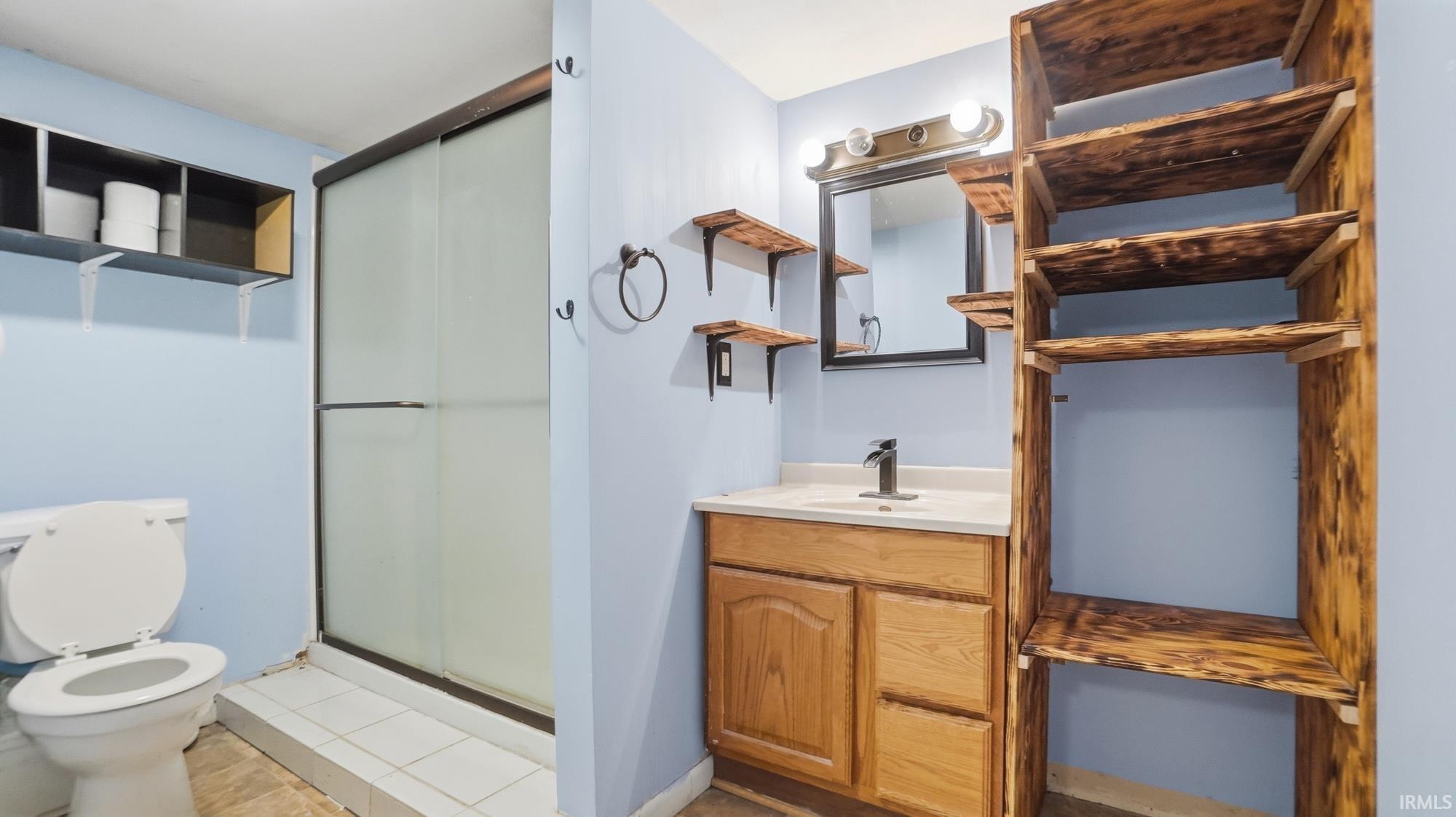 Bathroom featuring vanity, a shower stall, and light tile patterned floors