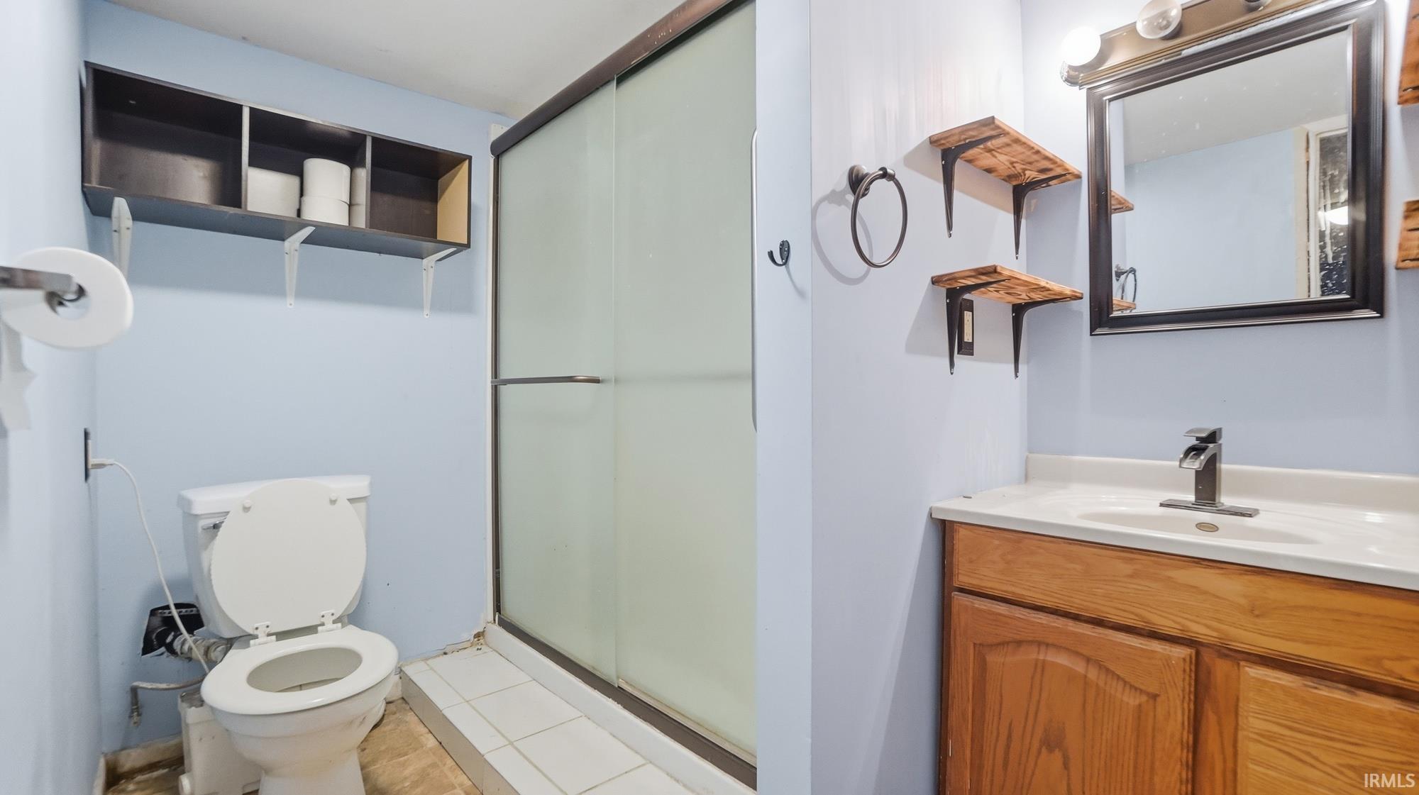 Bathroom with vanity, a shower stall, and light tile patterned flooring