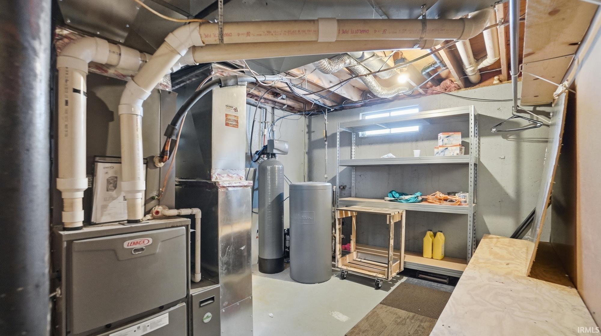 Unfinished below grade area with a water softener system and heating unit