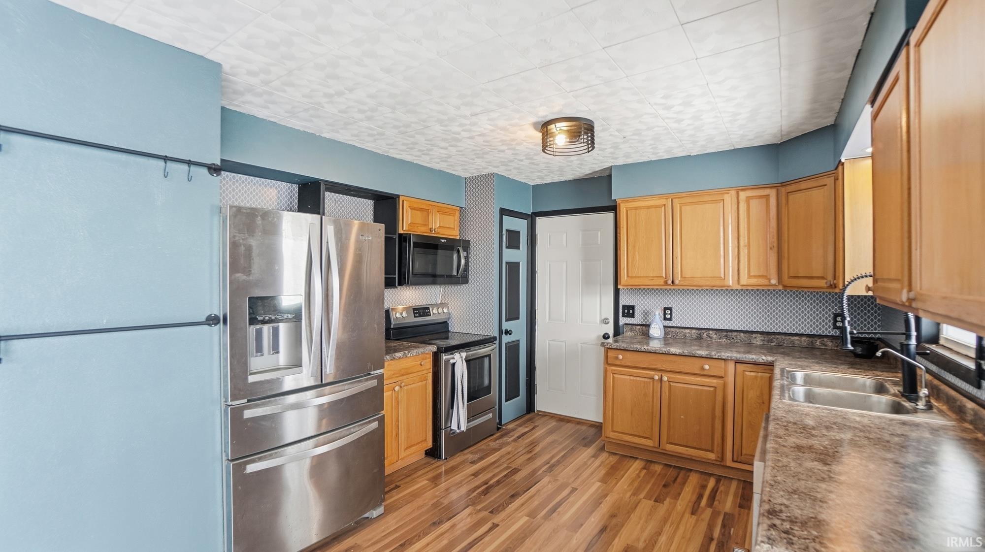 Kitchen featuring dark countertops, stainless steel appliances, and light wood-style flooring